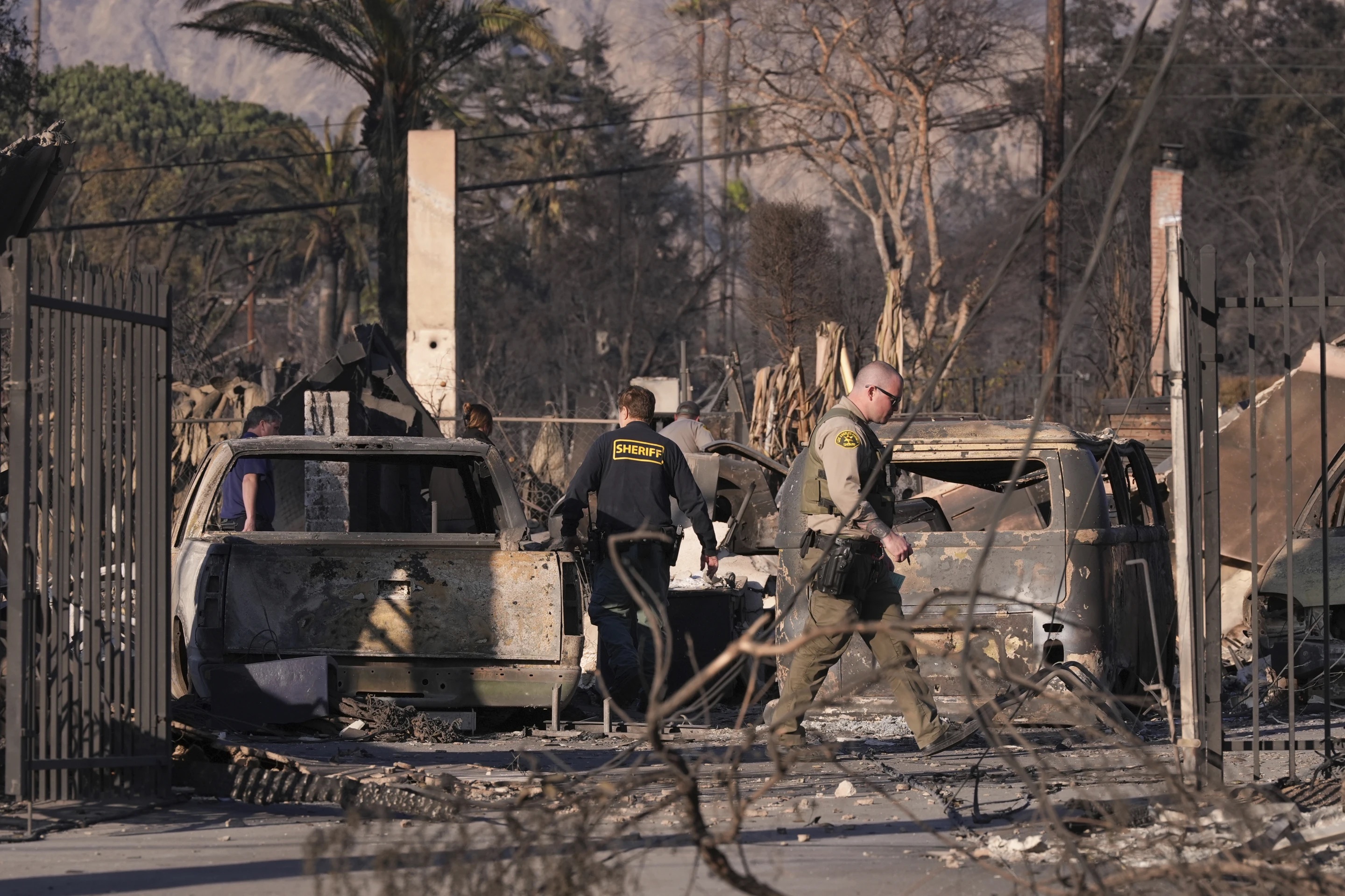 A medical examiner and sheriff's deputies check on a home destroyed by the Eaton Fire on Saturday, in Altadena, Calif.