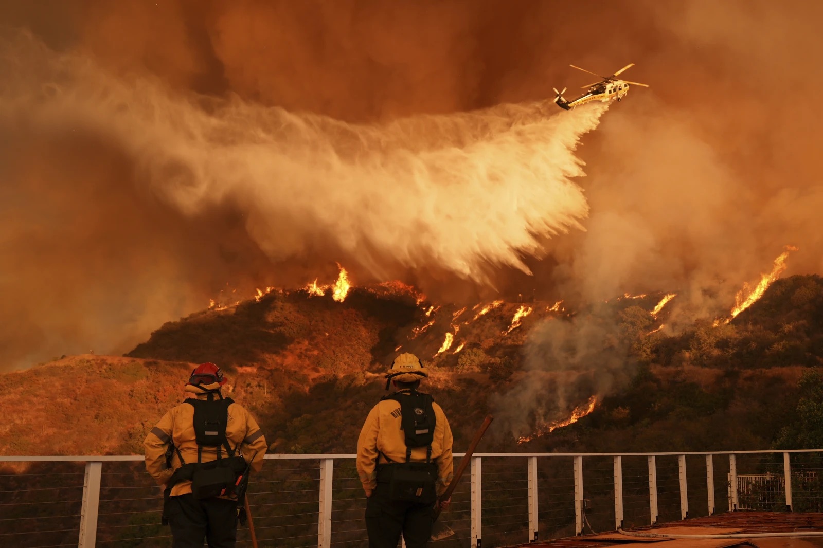 Firefighters watch as water is dropped on the Palisades Fire in Mandeville Canyon Saturday, in Los Angeles.