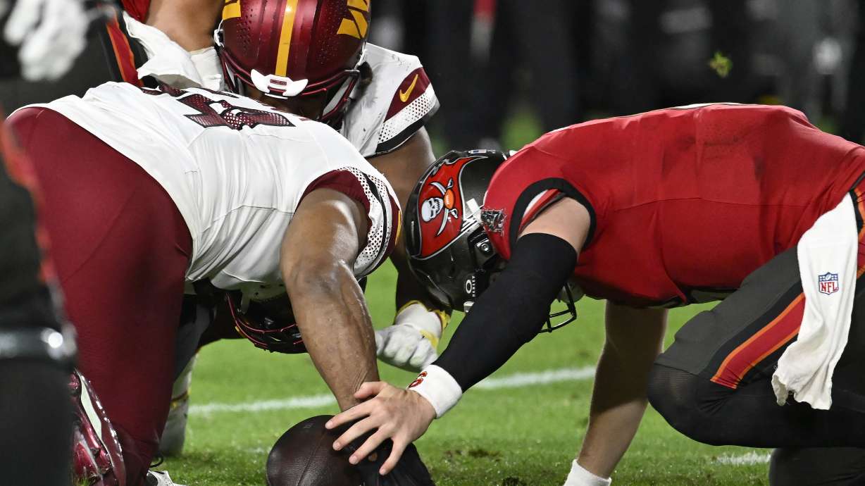 Washington Commanders linebacker Bobby Wagner, left, recovers a fumble by Tampa Bay Buccaneers quarterback Baker Mayfield, right, during the second half of an NFL wild-card playoff football game in Tampa, Fla., Sunday, Jan. 12, 2025.