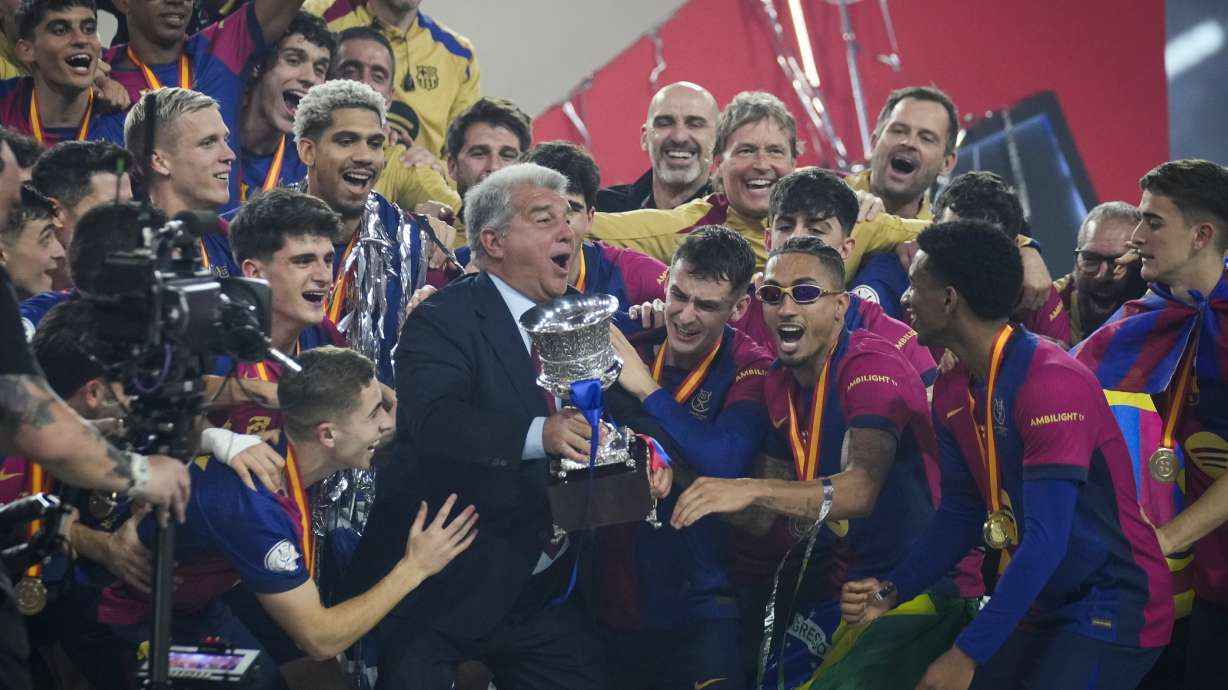 President of Barcelona Joan Laporta, centre, and his players celebrate with the trophy after winning the Spanish Super Cup against Real Madrid at King Abdullah Stadium in Jeddah, Saudi Arabia, Monday, Jan. 13, 2025.