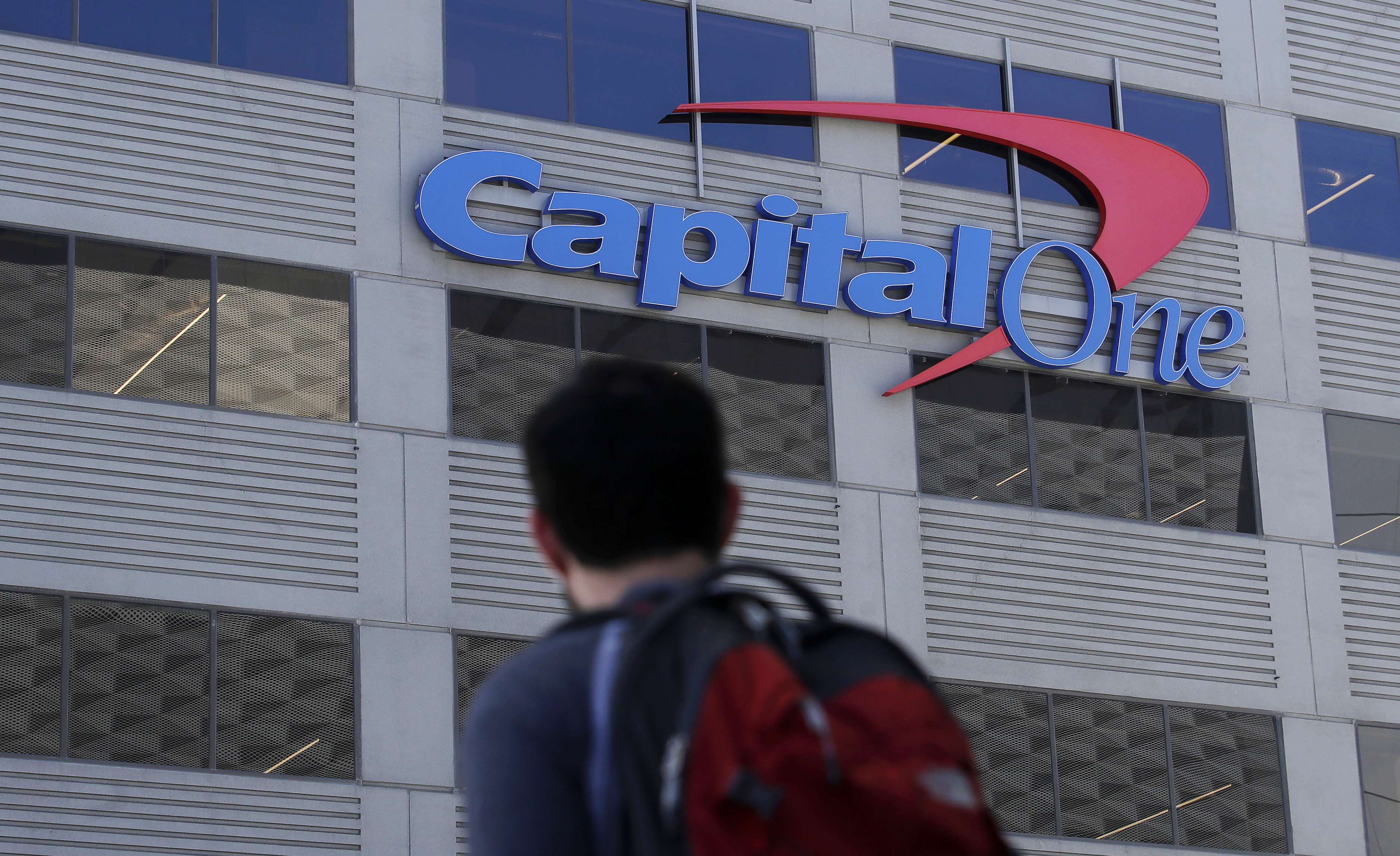A man walks across the street from a Capital One location in San Francisco. The bank was sued by a U.S. watchdog after it was accused of cheating customers out of $2 billion.