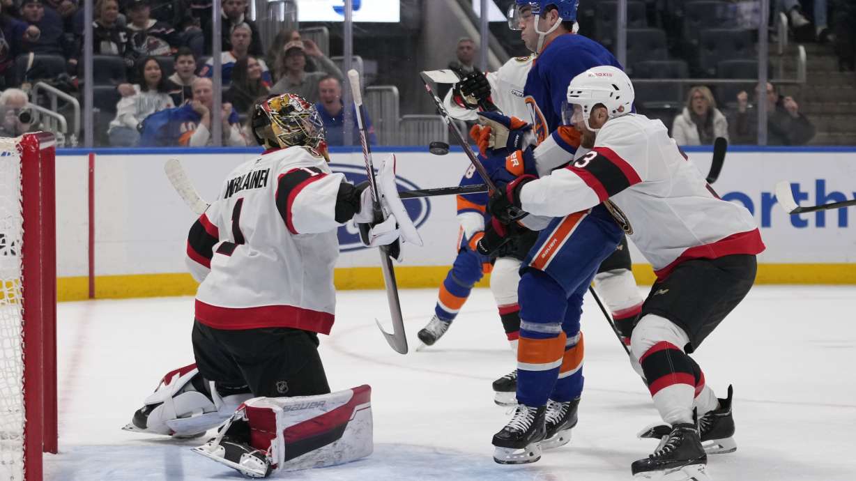 Ottawa Senators goaltender Leevi Merilainen (1) stops a shot by New York Islanders' Noah Dobson (8) as Nick Jensen (3) defends during the second period of an NHL hockey game, Tuesday, Jan. 14, 2025, in Elmont, N.Y.