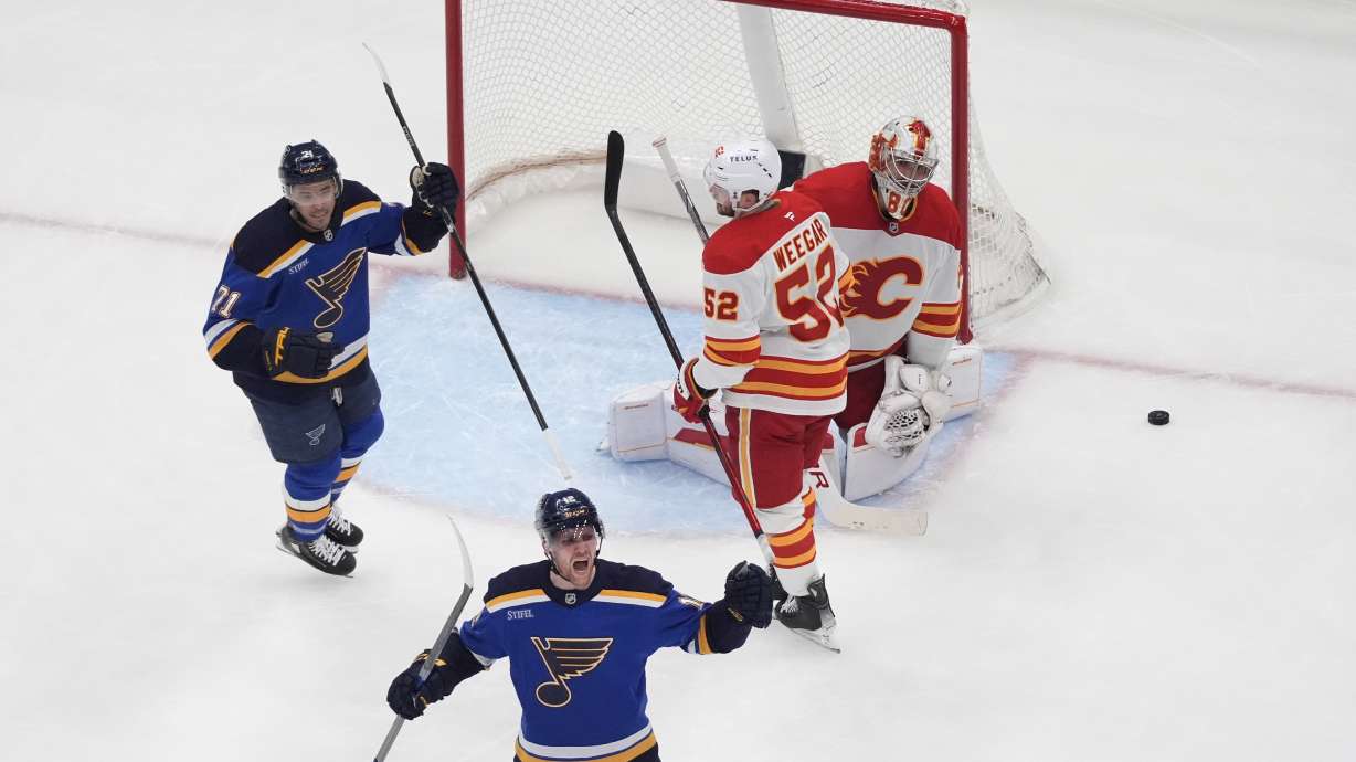 St. Louis Blues' Radek Faksa, bottom, celebrates after scoring past Calgary Flames' MacKenzie Weegar (52) and goaltender Dan Vladar (80) as teammate Mathieu Joseph (71) looks on during the third period of an NHL hockey game Tuesday, Jan. 14, 2025, in St. Louis.