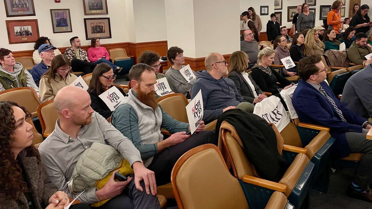 Audience members at an Ogden City Council meeting on Tuesday, when the officials considered a proposal to develop a facility for the chronically homeless in the city. The "vote yes" signs tout approval of the plans.