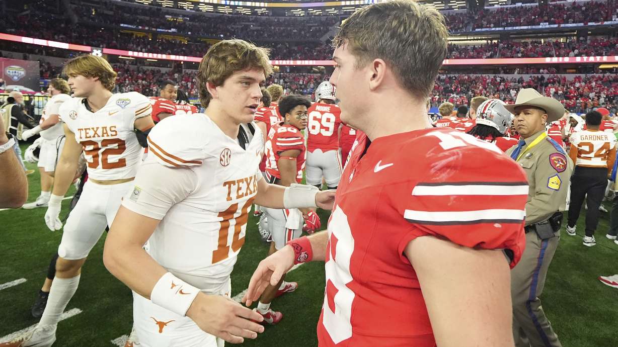 Texas quarterback Arch Manning, middle left, shakes hands with Ohio State quarterback Will Howard after the Cotton Bowl College Football Playoff semifinal game, Friday, Jan. 10, 2025, in Arlington, Texas.
