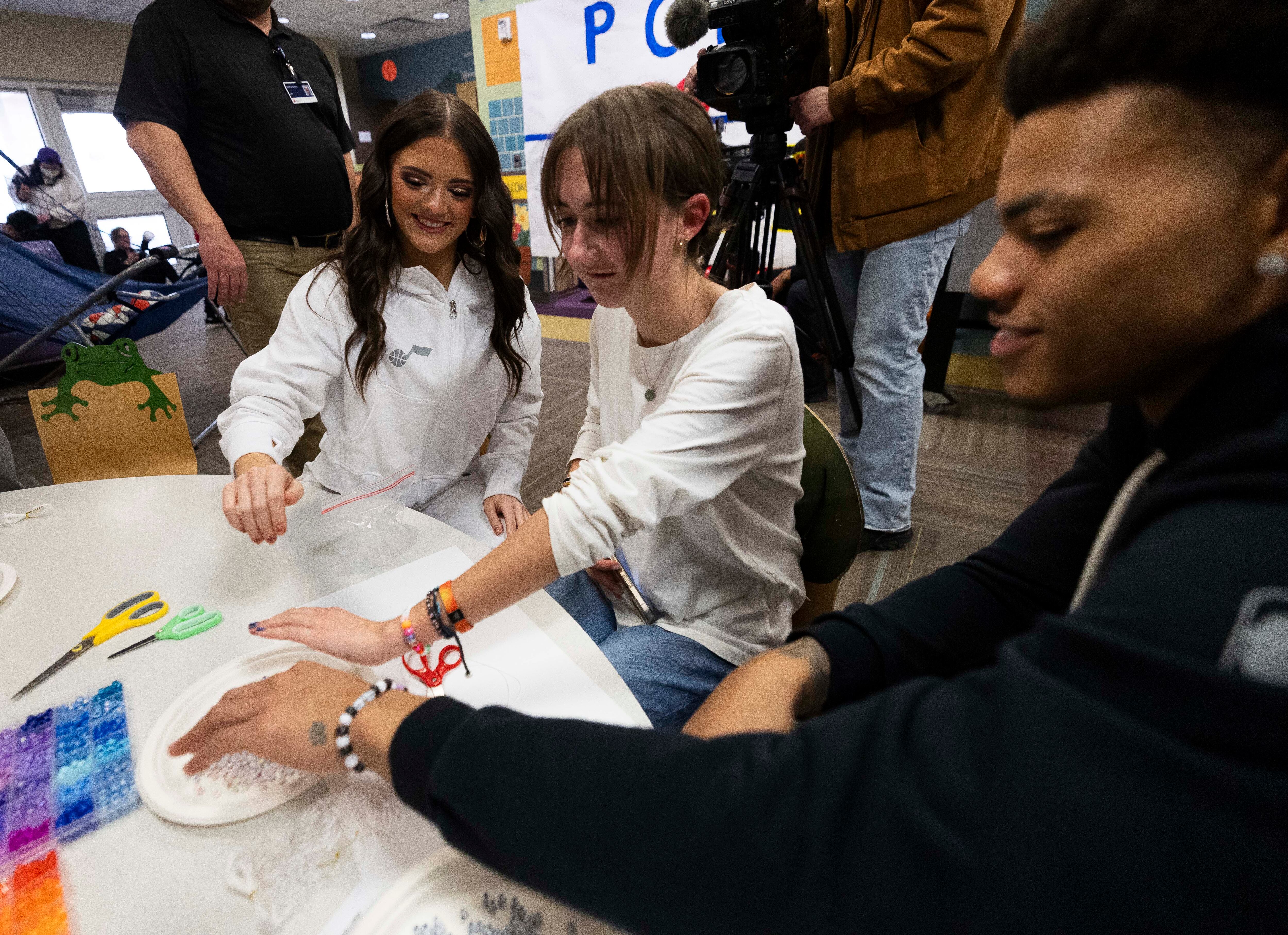 Jazz dancer Grace Poulsen, left, Shelby Lunt, 17, center, and Utah Jazz guard Keyonte George all hold their arms out together while admiring the bracelets they helped each other make during a Utah Jazz visit to Intermountain Primary Children’s Hospital in Salt Lake City on Tuesday.