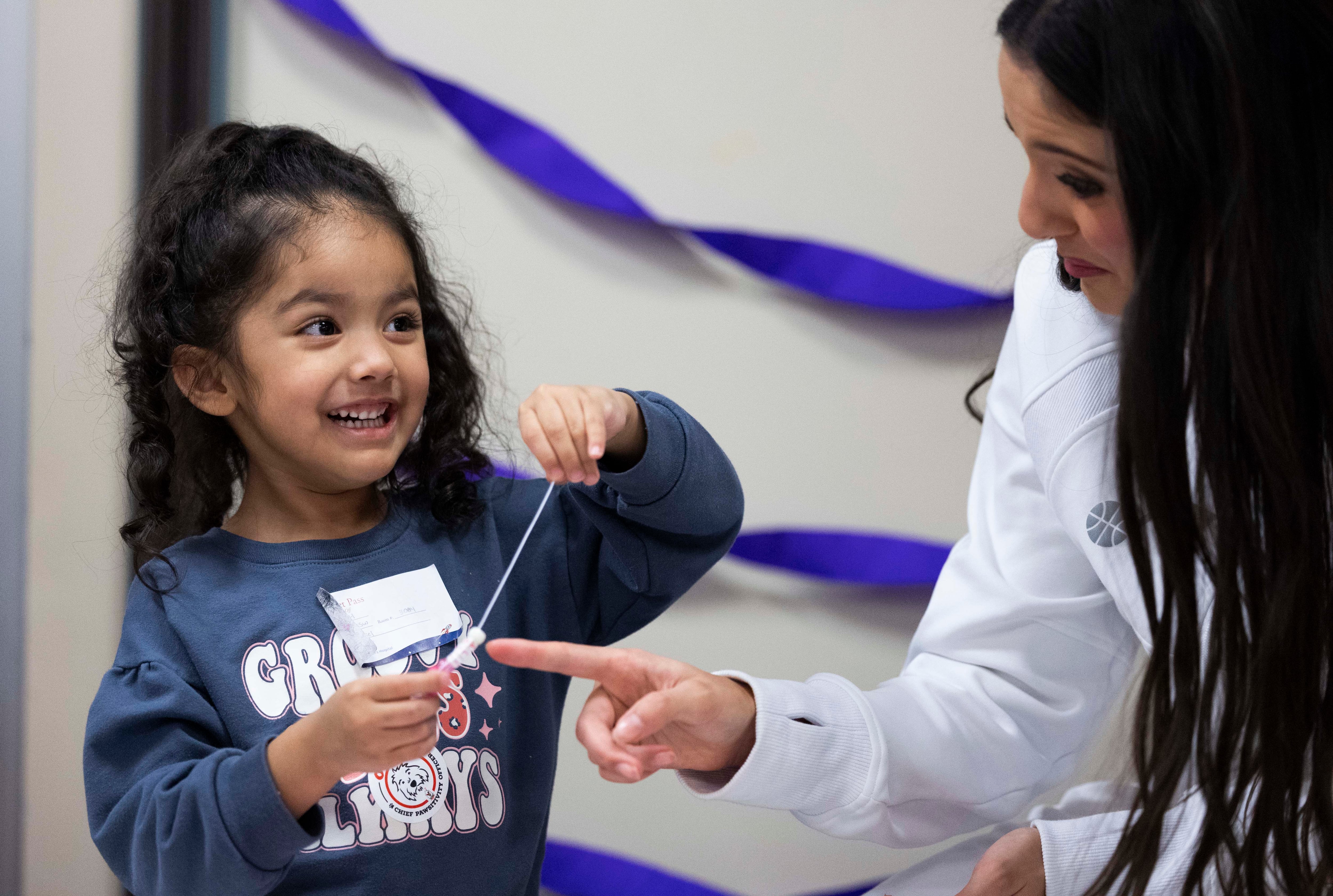 Ali Silva, 3, laughs with Jazz dancer Halle Santiago while making bracelets during a Utah Jazz visit to Intermountain Primary Children’s Hospital in Salt Lake City on Tuesday.