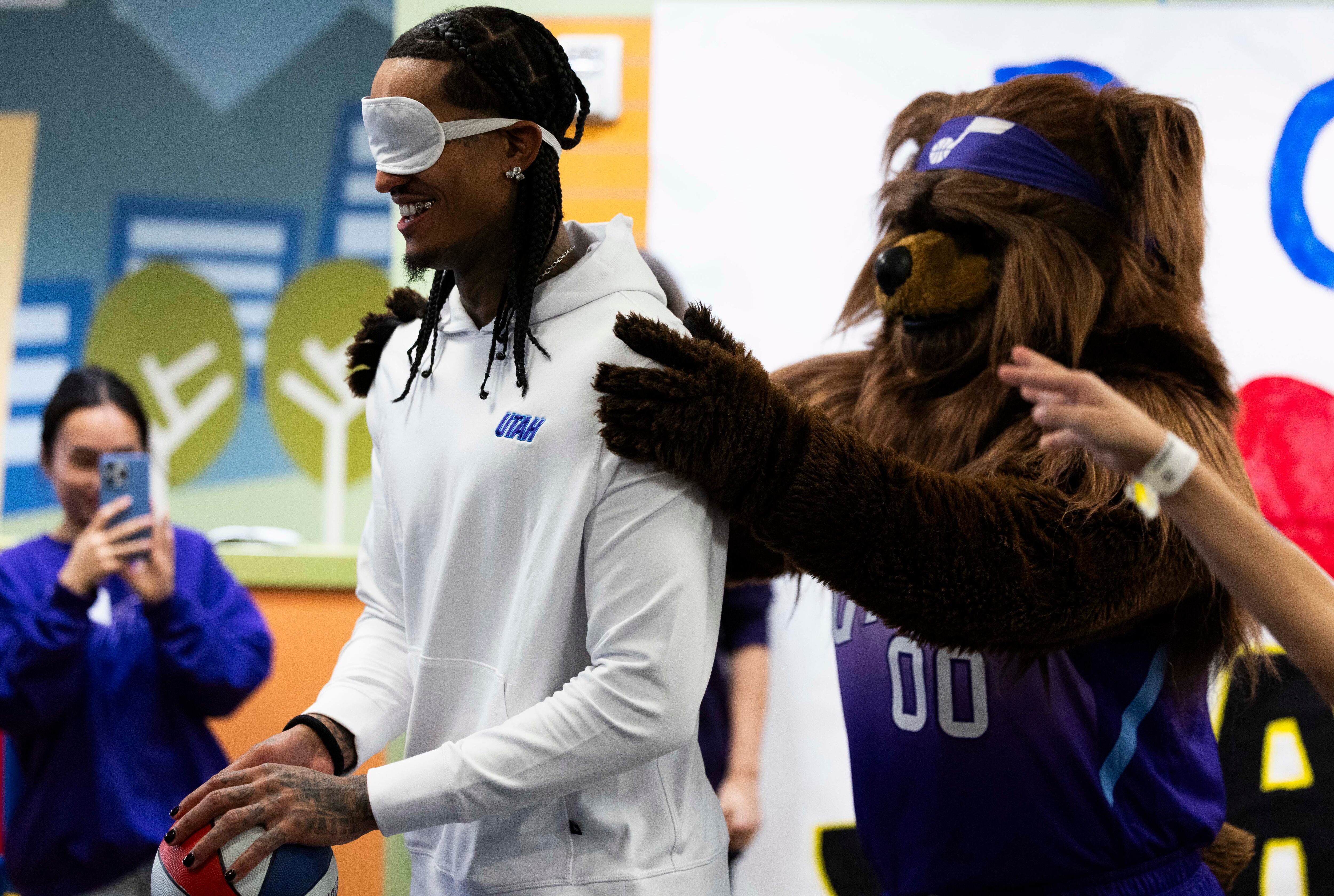 Jazz Bear faces a blindfolded Utah Jazz guard Jordan Clarkson toward a basketball hoop during a Utah Jazz visit to Intermountain Primary Children’s Hospital in Salt Lake City on Tuesday.