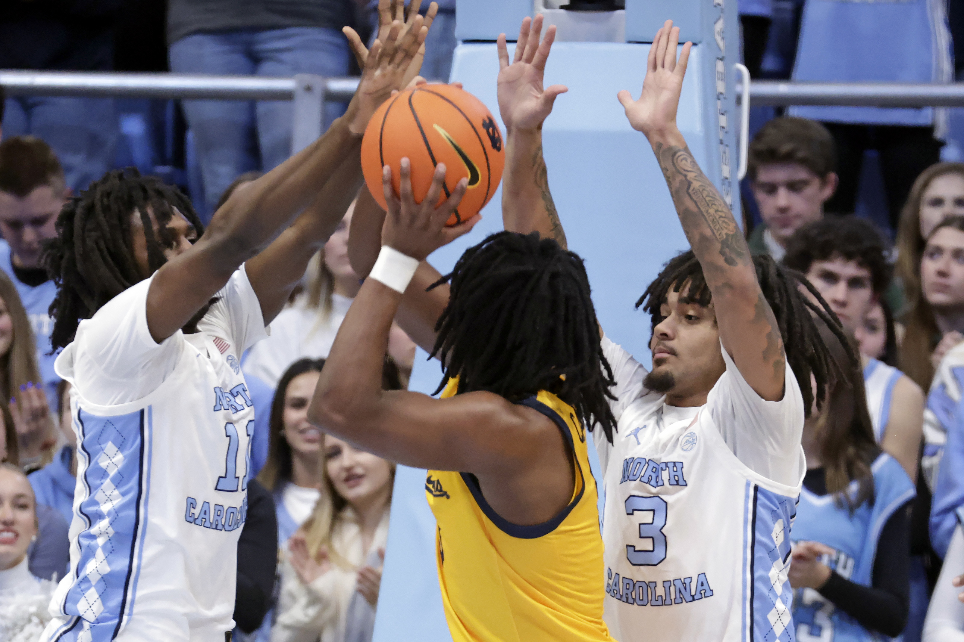 North Carolina guard Ian Jackson (11) and guard Elliot Cadeau (3) defend California guard DJ Campbell, center, during the first half of an NCAA college basketball game Wednesday, Jan. 15, 2025, in Chapel Hill, N.C. 