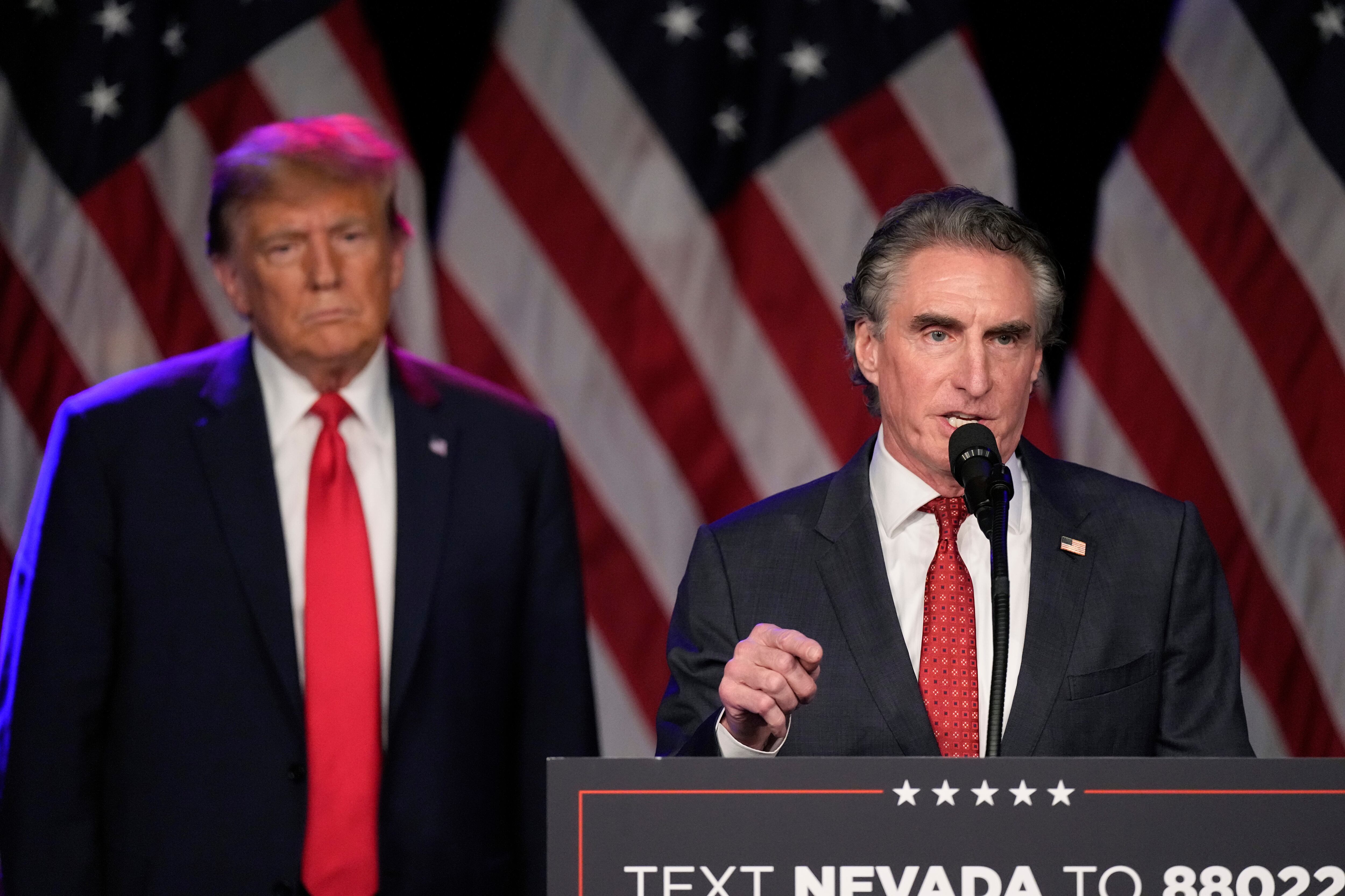 Republican presidential candidate former President Donald Trump listens as North Dakota Gov. Doug Burgum speaks at a caucus night rally in Las Vegas, Feb. 8, 2024.