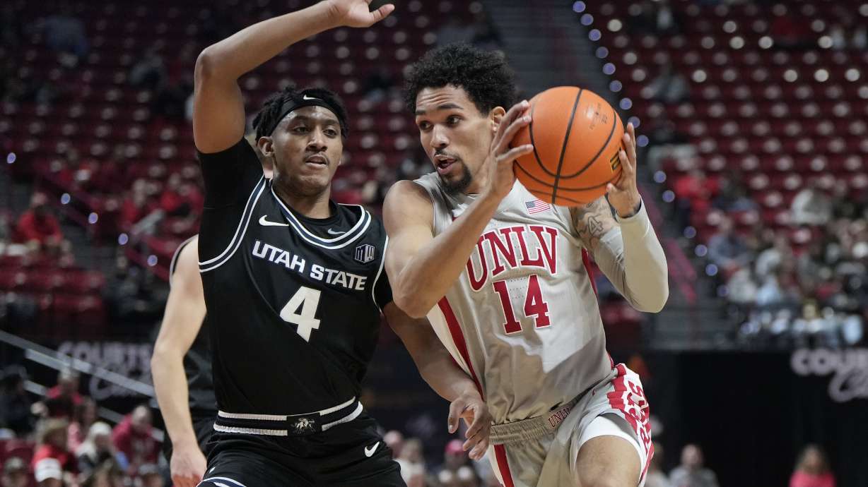 UNLV guard Jailen Bedford (14) drives the ball against Utah State guard Ian Martinez (4) during the first half of an NCAA college basketball game, Wednesday, Jan. 15, 2025, in Las Vegas.