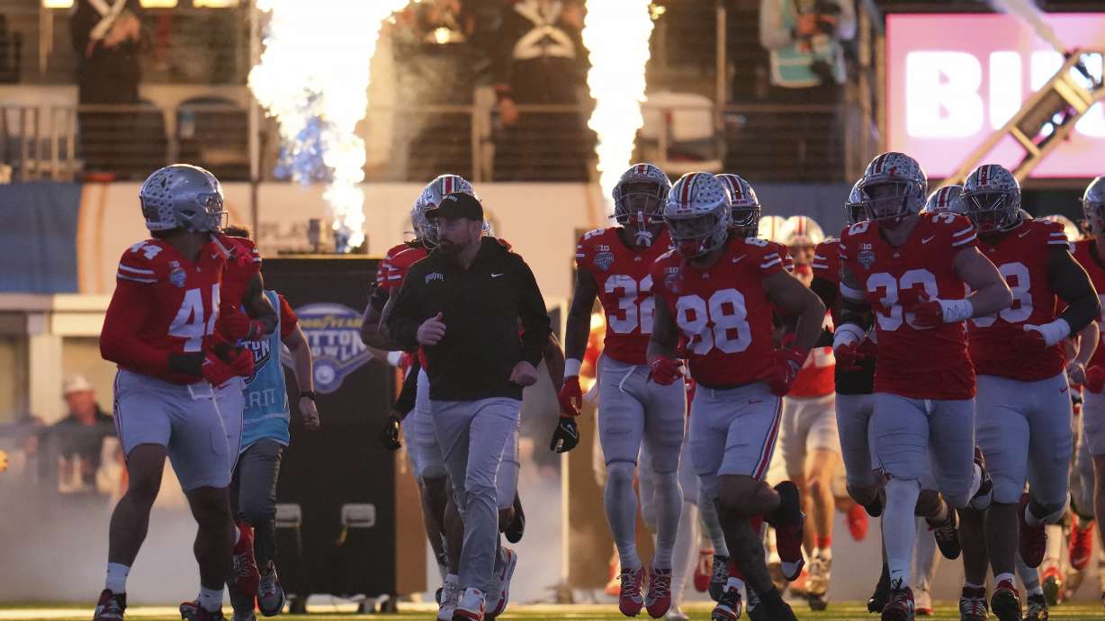 Ohio State head coach Ryan Day, middle left, runs onto the field with players before the Cotton Bowl College Football Playoff semifinal game against Texas, Friday, Jan. 10, 2025, in Arlington, Texas.