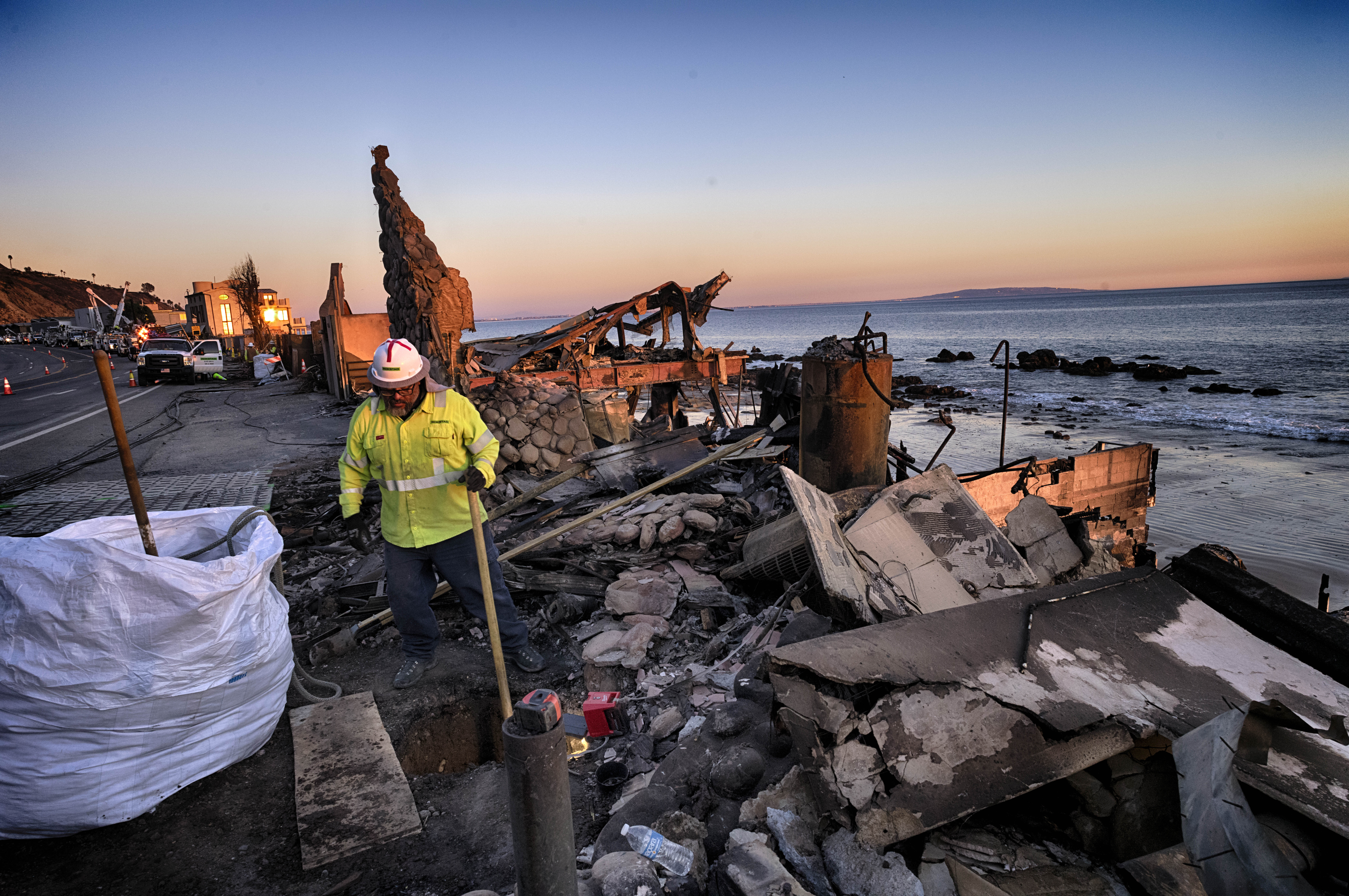 A crew for Southern California Edison prepares the ground for electric poles along the Pacific Coast Highway near homes destroyed from the Pacific Palisades Fire in Malibu, Calif., Wednesday. Jan. 15.