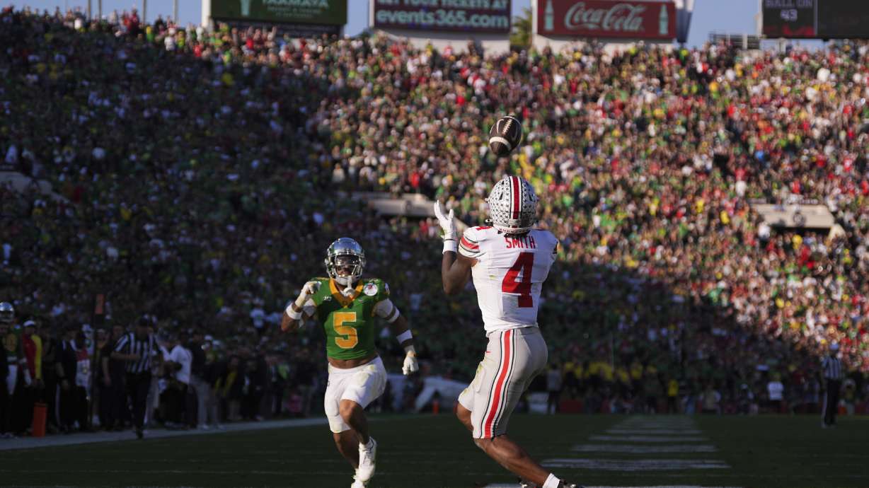 Ohio State wide receiver Jeremiah Smith (4) catches a touchdown pass against Oregon defensive back Kobe Savage (5) during the first half in the quarterfinals of the Rose Bowl College Football Playoff, Wednesday, Jan. 1, 2025, in Pasadena, Calif.