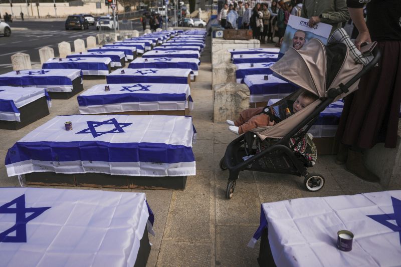 People stand by coffins lining a street and covered with Israeli flags that are meant to symbolize the price Israel will pay for agreeing to a ceasefire with Hamas in a demonstration against the deal staged by a group representing families of Israelis killed during the war in Gaza, in Jerusalem on Thursday.