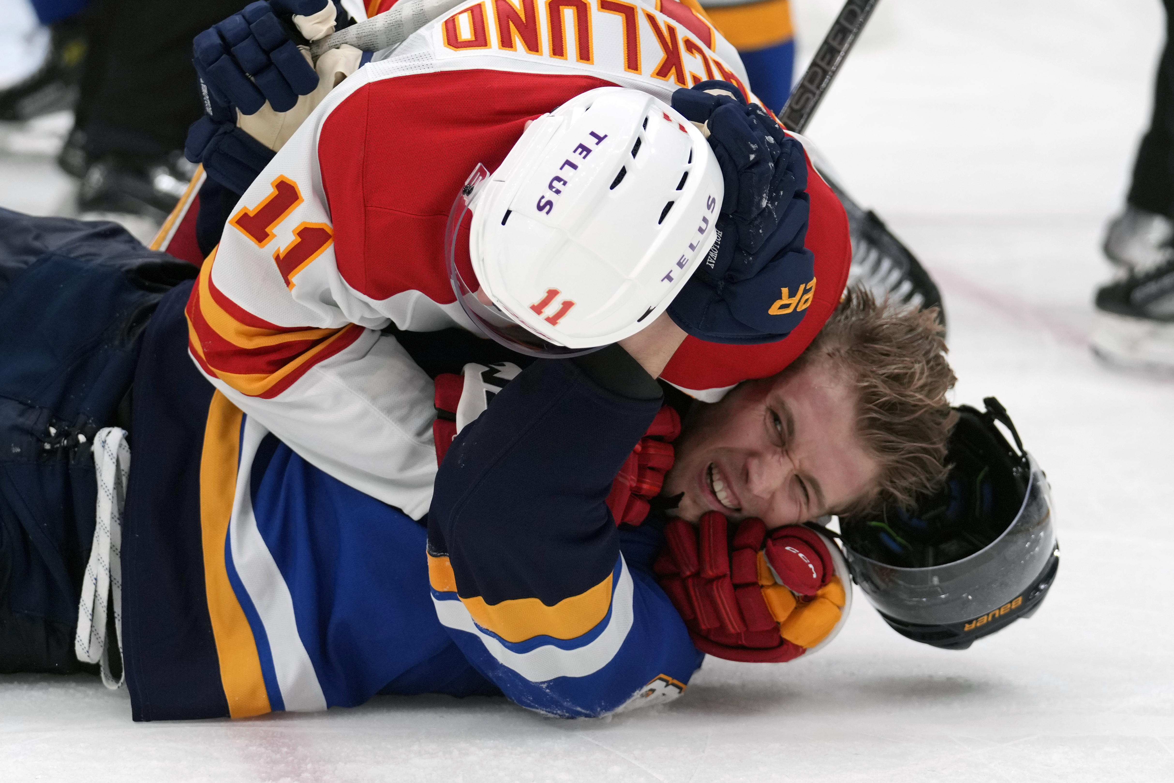 St. Louis Blues' Dylan Holloway and Calgary Flames' Mikael Backlund (11) fight during the second period of an NHL hockey game Thursday, Jan. 16, 2025, in St. Louis.