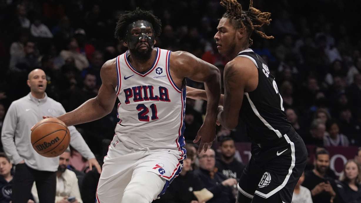 Philadelphia 76ers' Joel Embiid (21) drives past Brooklyn Nets' Jalen Wilson (22) during the second half of an NBA basketball game Saturday, Jan. 4, 2025, in New York.