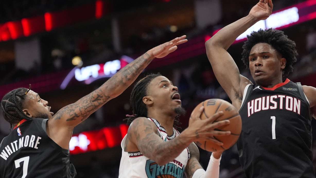 Memphis Grizzlies' Ja Morant (12) goes up for a shot as Houston Rockets' Cam Whitmore (7) and Amen Thompson (1) defends during the second half of an NBA basketball game Monday, Jan. 13, 2025, in Houston. The Rockets won 120-118.