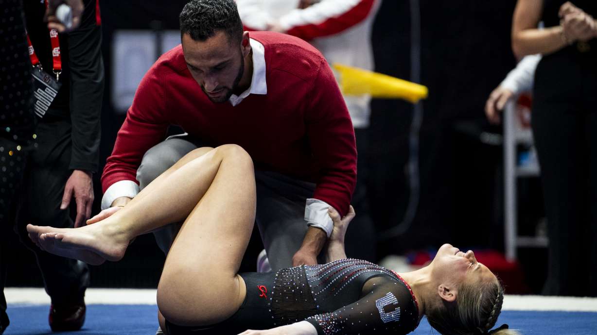 Utah Red Rocks’ Avery Neff is tended to by athletic trainer Zeb Callahan after she sustained an injury competing in the floor routine during a gymnastics meet against Iowa State University held at the Huntsman Center in Salt Lake City on Friday, Jan. 17, 2025.