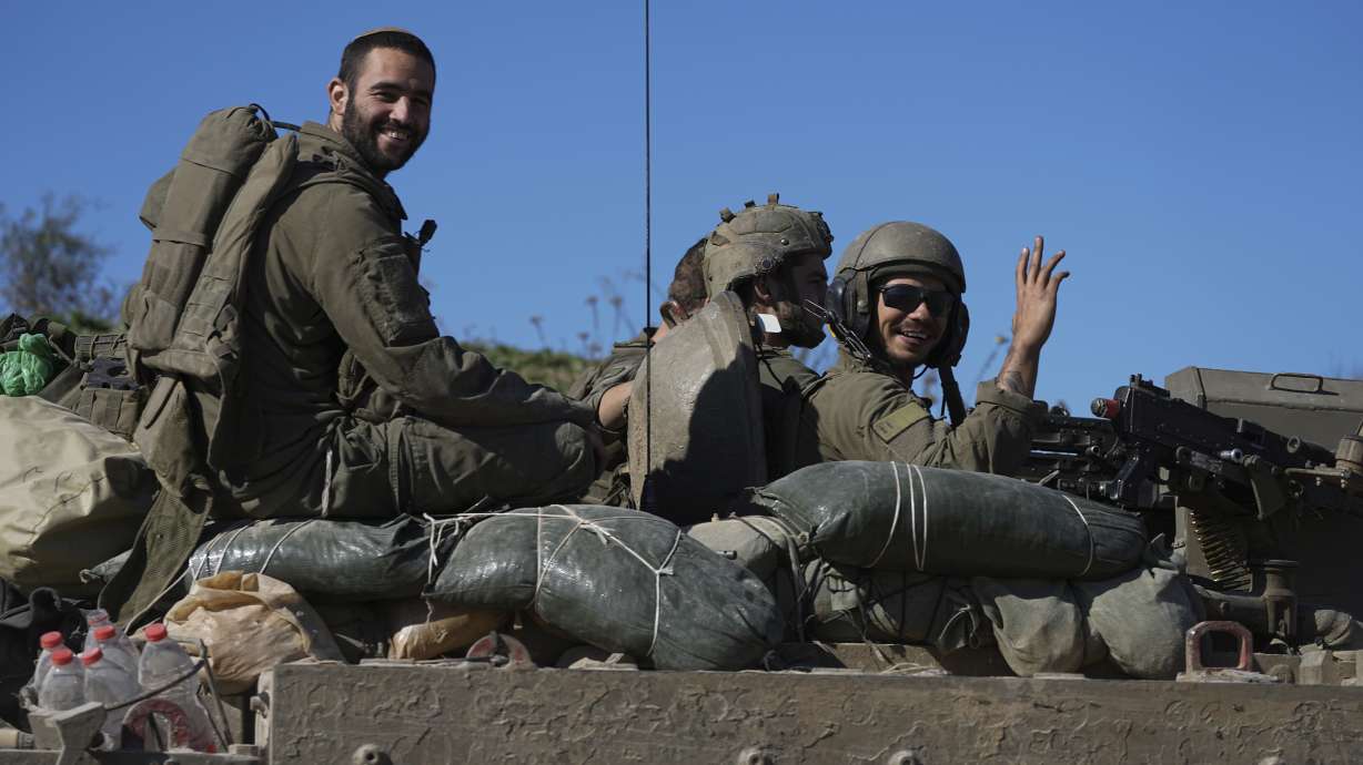 Israeli soldiers wave to the camera from an APC as they cross from the Gaza Strip into Israel, Saturday. The ceasefire between Hamas and Israel will go into effect Sunday morning.