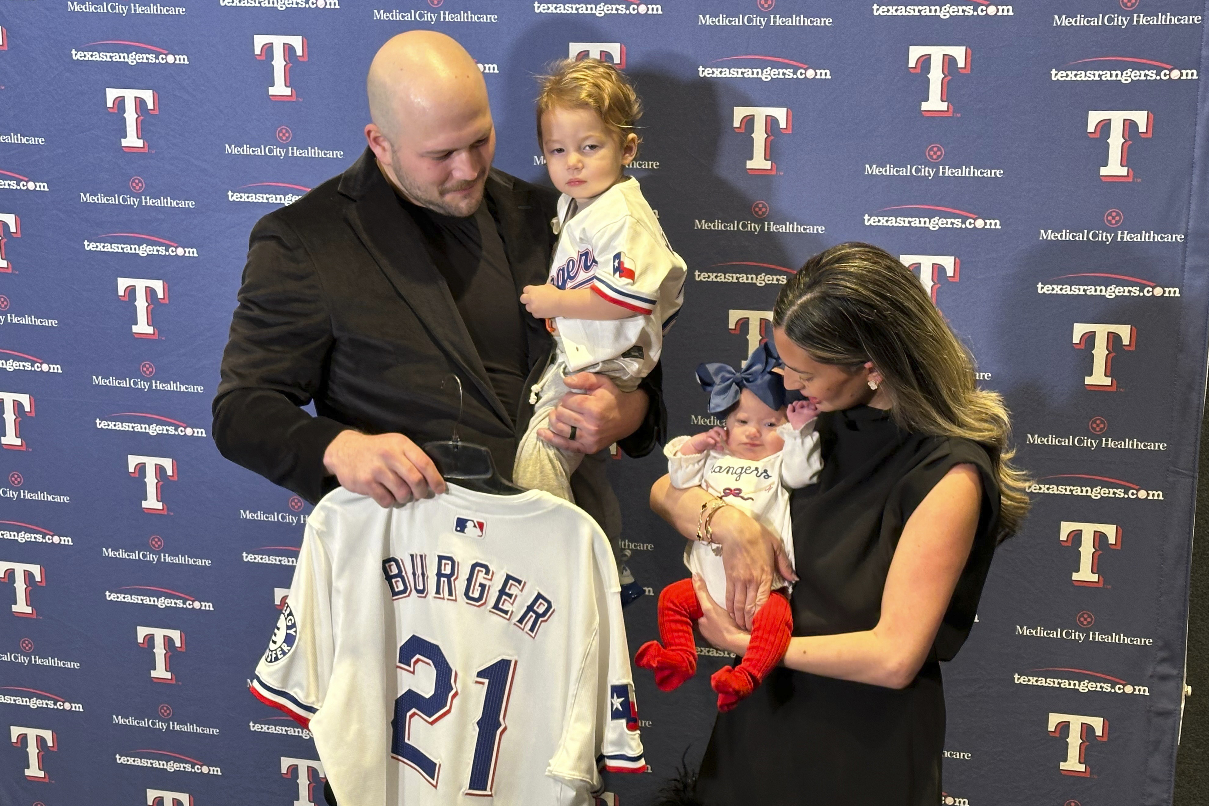 Texas Rangers first baseman Jake Burger poses at the team's awards dinner Friday, Jan. 17, 2025, in Arlington, Texas, with wife Ashyln, son Brooks and daughter Penelope while holding the No. 21 jersey that has special significance after his daughter was born with Down syndrome.