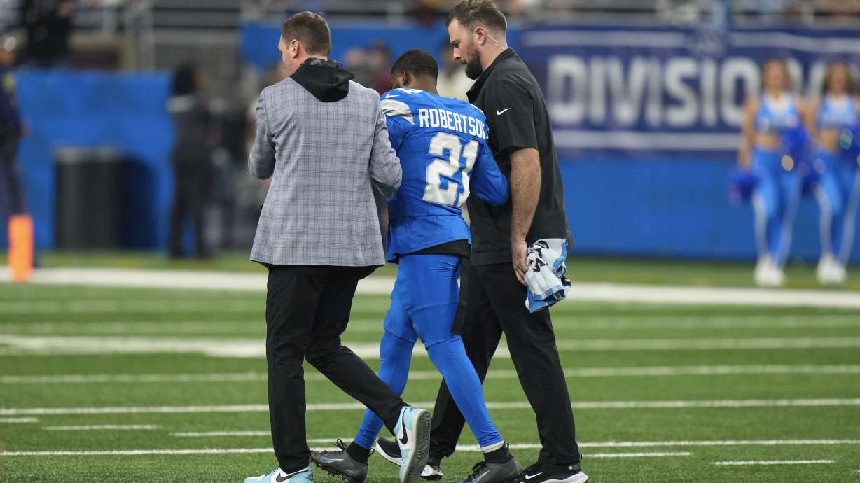 Detroit Lions cornerback Amik Robertson (21) is helped off the field against the Washington Commanders after being injured during the first half of an NFL football divisional playoff game, Saturday, Jan. 18, 2025, in Detroit.