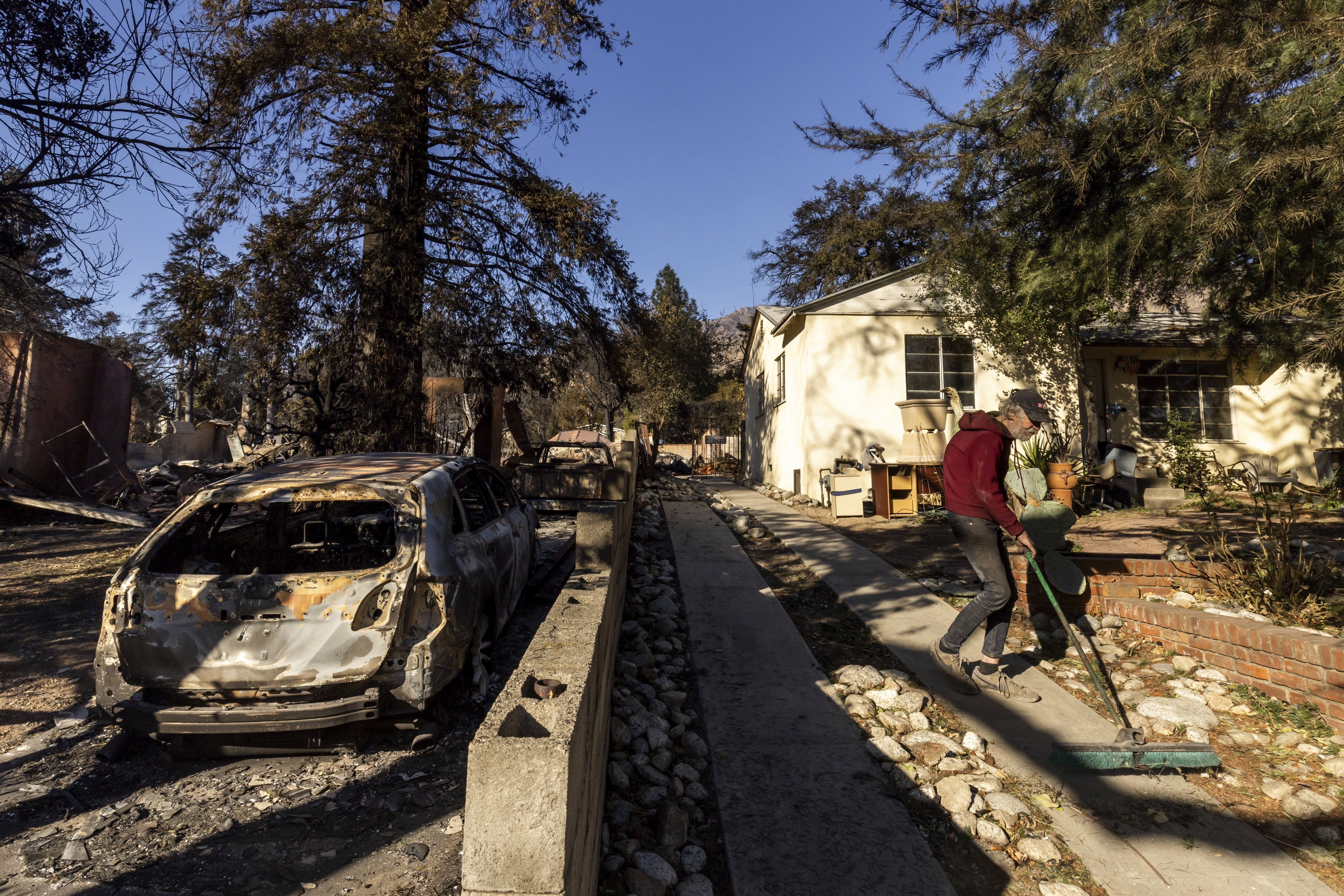 David Slater, right, clears the driveway from his home, spared from the Eaton Fire, Jan. 12, in Altadena, Calif. 