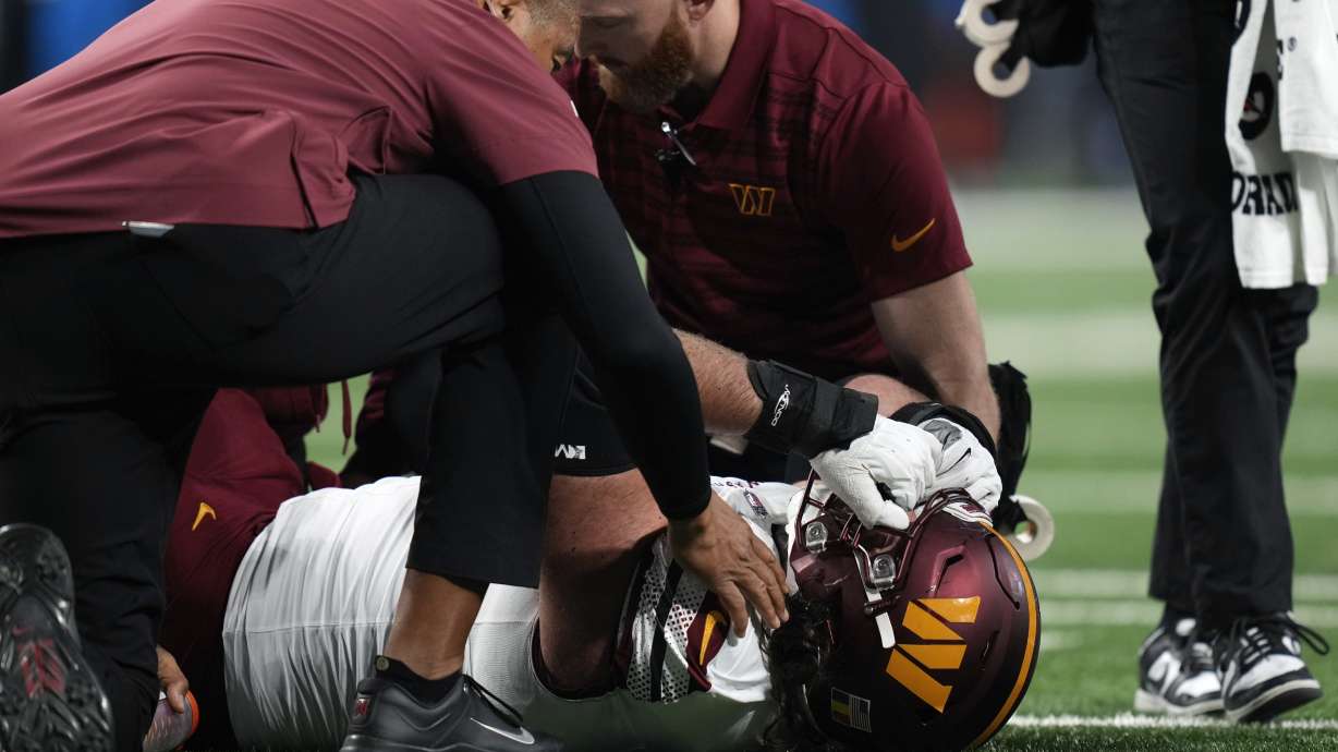 Washington Commanders guard Sam Cosmi (76) is helped by medical staff after being injured against the Detroit Lions during the first half of an NFL football divisional playoff game, Saturday, Jan. 18, 2025, in Detroit.