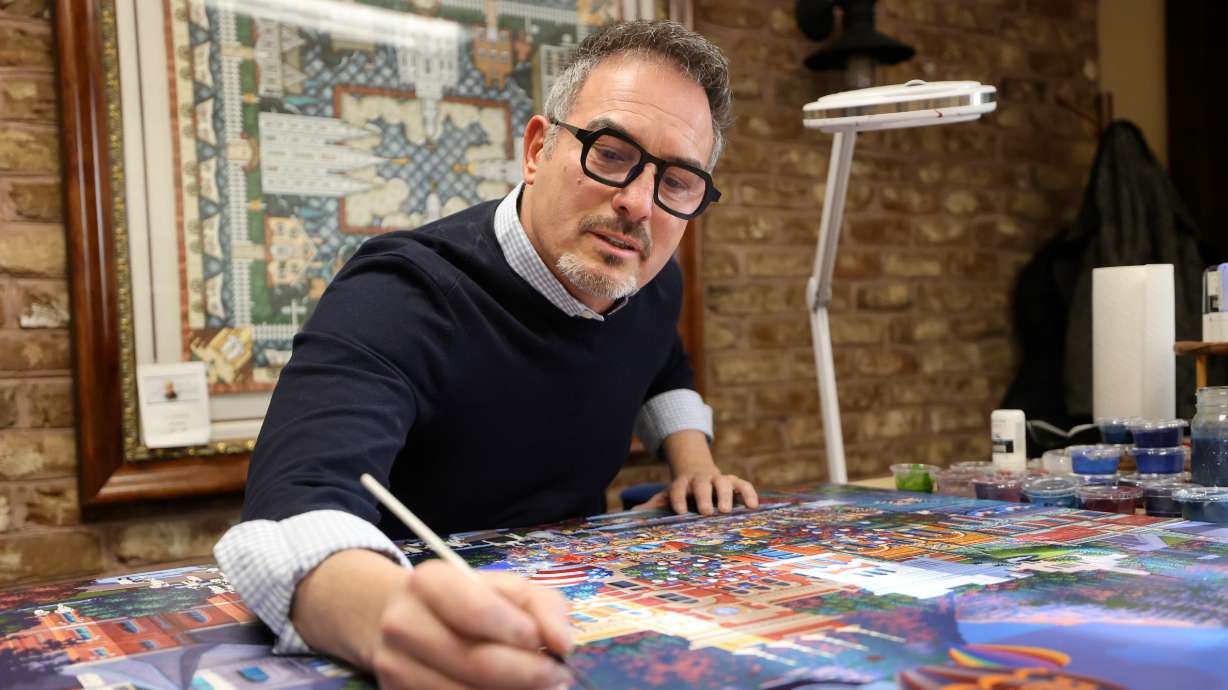 Artist Eric Dowdle paints a Provo Freedom Festival scene at Dowdle Puzzles in Lindon on Jan. 8. When he decided it was OK to carve his art into tiny pieces, he didn't do it halfway.