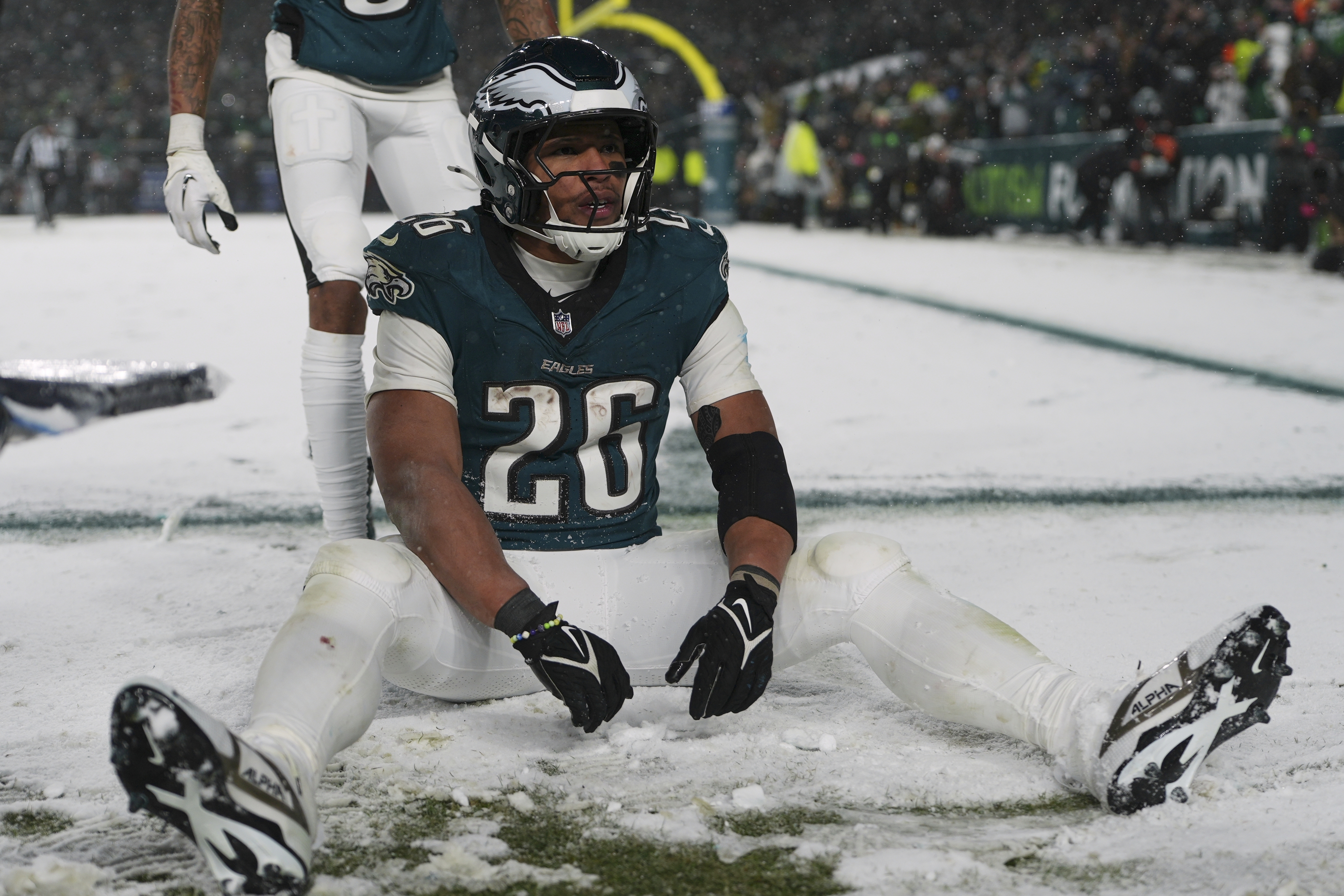 Philadelphia Eagles running back Saquon Barkley (26) sits in the snow as he celebrates his touchdown during the second half of an NFL football NFC divisional playoff game against the Los Angeles Rams on Sunday, Jan. 19, 2025, in Philadelphia.