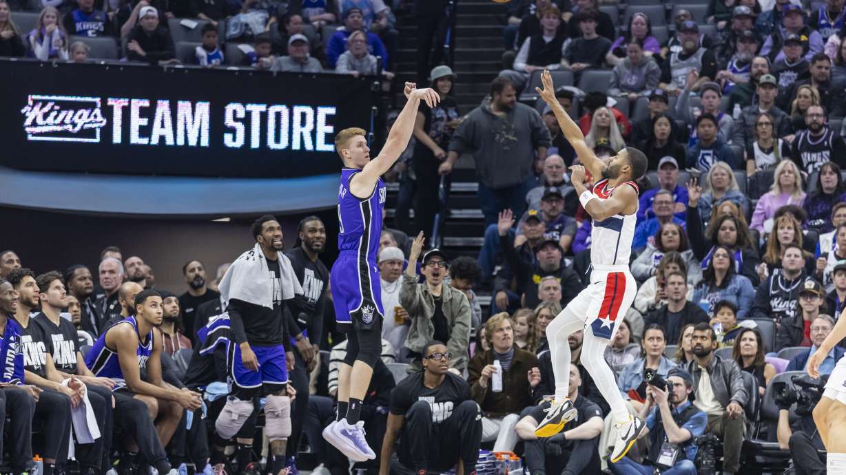 Sacramento Kings guard Kevin Huerter, center left, attempts a 3-point basket over Washington Wizards guard Jared Butler, center right, during the first half of an NBA basketball game Sunday, Jan. 19, 2025, in Sacramento, Calif.