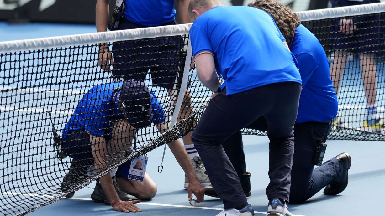 Staff work on repair the net during the fourth round match between Jannik Sinner of Italy and Holger Rune of Denmark at the Australian Open tennis championship in Melbourne, Australia, Monday, Jan. 20, 2025.