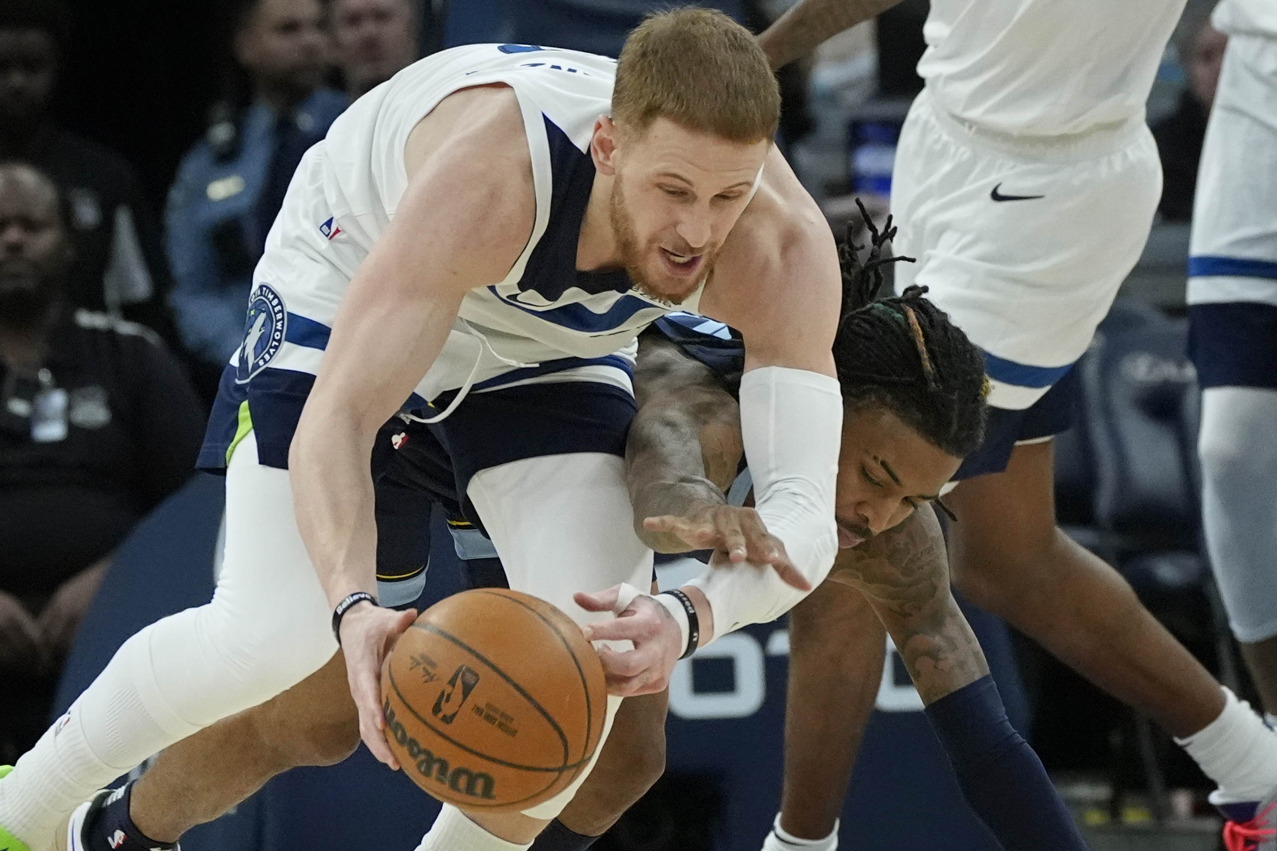 Minnesota Timberwolves guard Donte DiVincenzo, left, wins a battle for the ball over Memphis Grizzlies guard Ja Morant, right, in the third quarter of an NBA basketball game Saturday, Jan. 11, 2025, in Minneapolis.