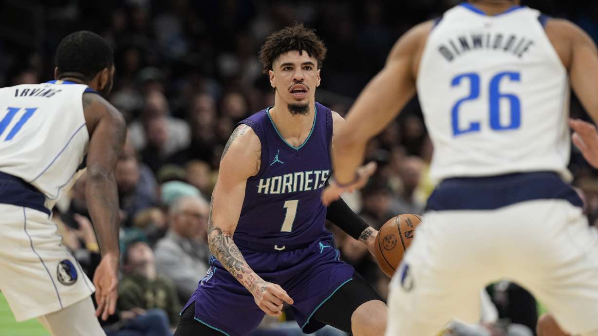Charlotte Hornets guard LaMelo Ball (1) handles the ball against Dallas Mavericks guard Kyrie Irving (11) and guard Spencer Dinwiddie (26) during the first half of an NBA basketball game on Monday, Jan. 20, 2025, in Charlotte, N.C.