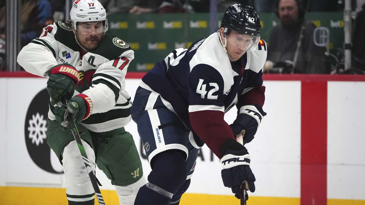 Colorado Avalanche defenseman Josh Manson, right, collects the puck as Minnesota Wild left wing Marcus Foligno defends in the second period of an NHL hockey game Monday, Jan. 20, 2025, in Denver.