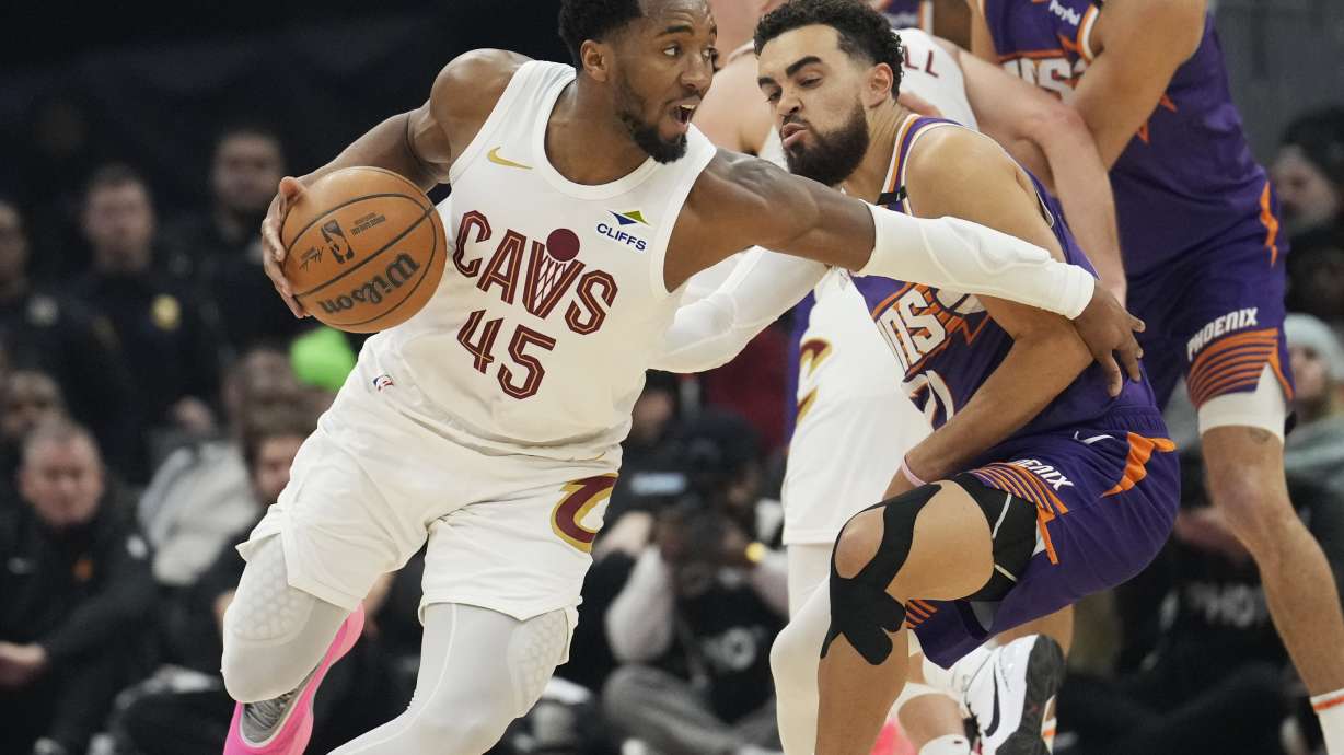 Cleveland Cavaliers guard Donovan Mitchell (45) drives around Phoenix Suns guard Tyus Jones, front right, in the first half of an NBA basketball game, Monday, Jan. 20, 2025, in Cleveland.