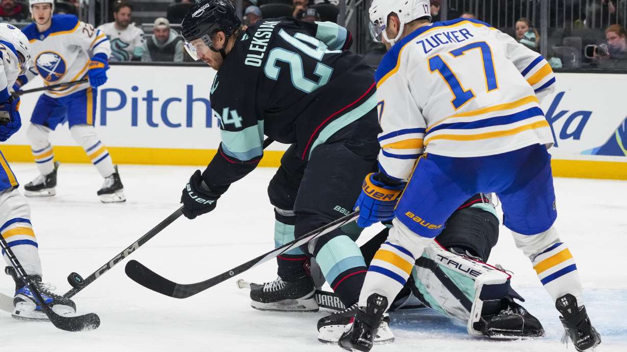 Seattle Kraken defenseman Jamie Oleksiak (24) blocks a shot against the Buffalo Sabres as left wing Jason Zucker (17) looks on during the third period of an NHL hockey game Monday, Jan. 20, 2025, in Seattle.
