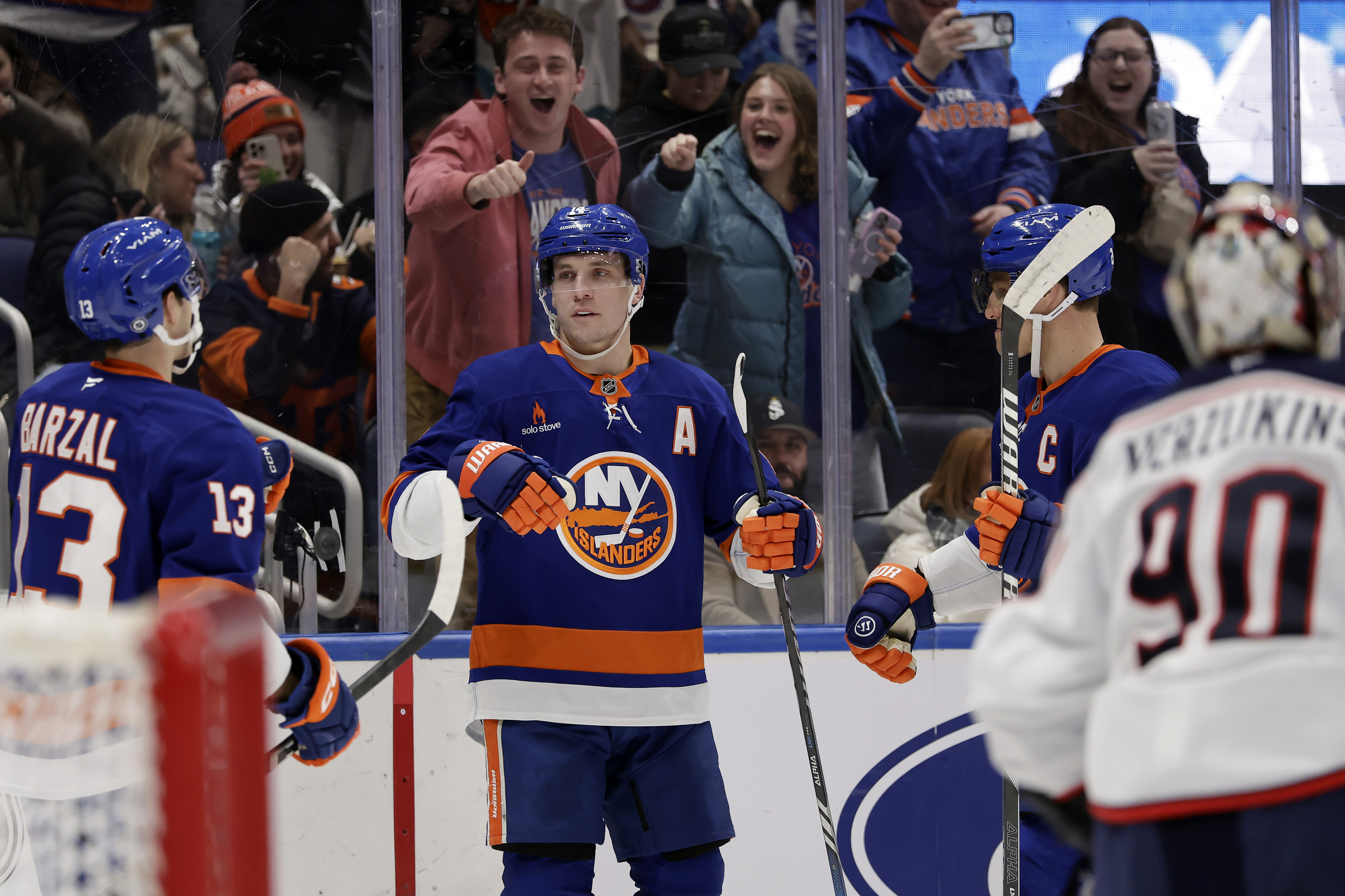 New York Islanders center Bo Horvat, center, is congratulated by Mathew Barzal (13) after scoring against Columbus Blue Jackets goaltender Elvis Merzlikins, right, in the second period of an NHL hockey game Monday, Jan. 20, 2025, in Elmont, N.Y.