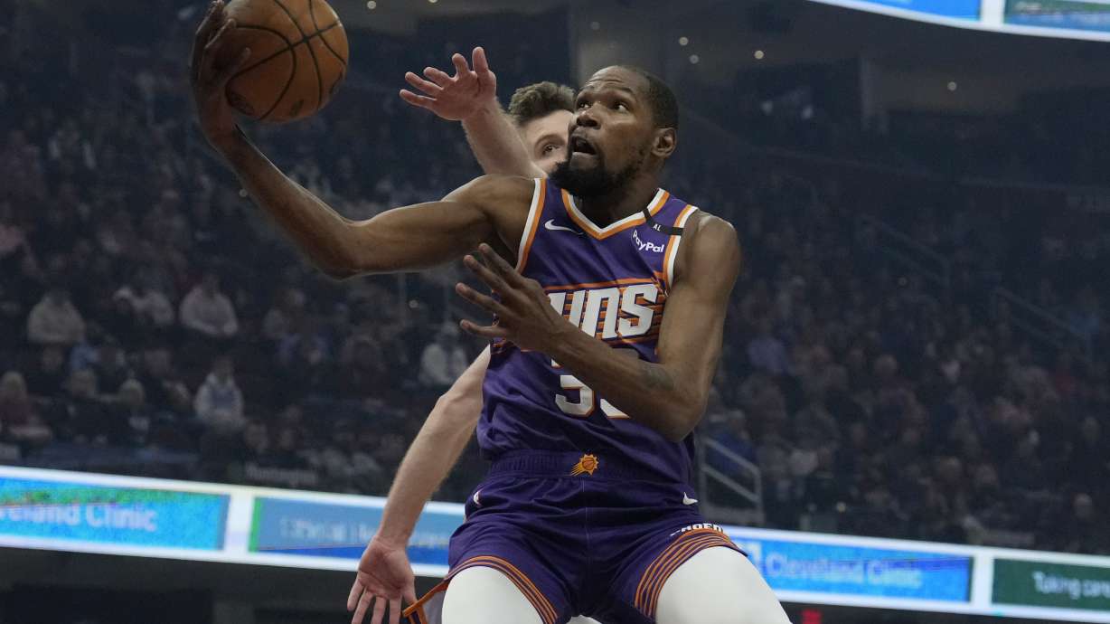 Phoenix Suns forward Kevin Durant, front, goes to the basket past Cleveland Cavaliers forward Dean Wade, back, in the first half of an NBA basketball game, Monday, Jan. 20, 2025, in Cleveland.