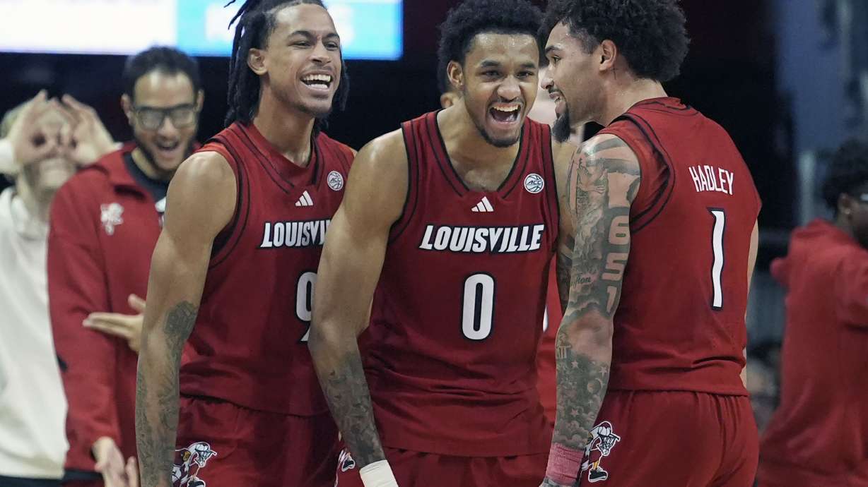 Louisville guard J'Vonne Hadley (1) celebrates with teammates forwards James Scott (0) and Khani Rooths (9) during the first half of an NCAA college basketball game against SMU Tuesday, Jan. 21, 2025, in Dallas.