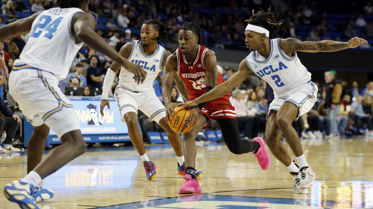 UCLA guard Dylan Andrews (2) attempts to steal the ball from Wisconsin guard John Blackwell, center, during the first half of an NCAA college basketball game Tuesday, Jan. 21, 2025, in Los Angeles.