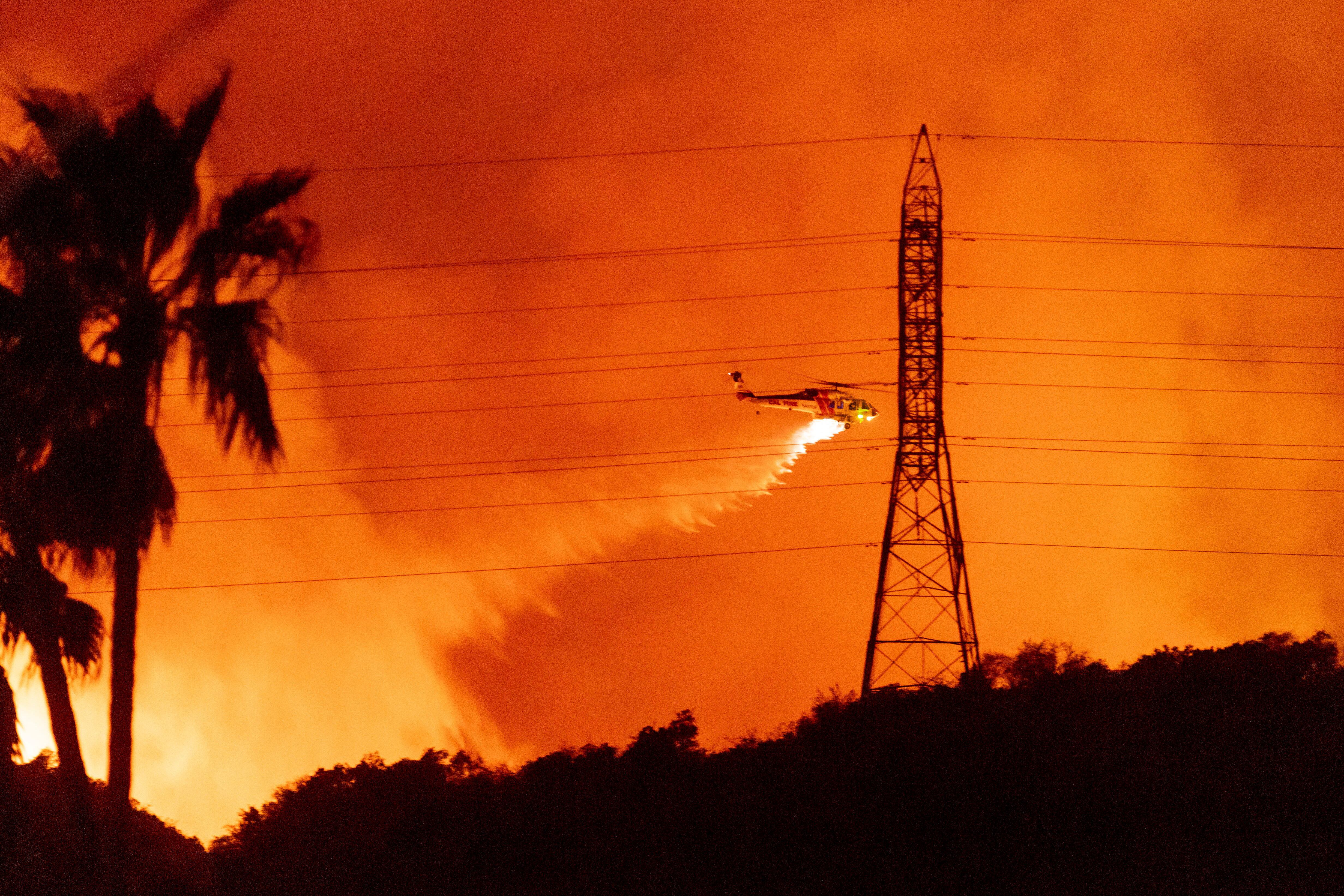 A helicopter drops water on the Palisades Fire in Mandeville Canyon, Jan. 10 in Los Angeles.