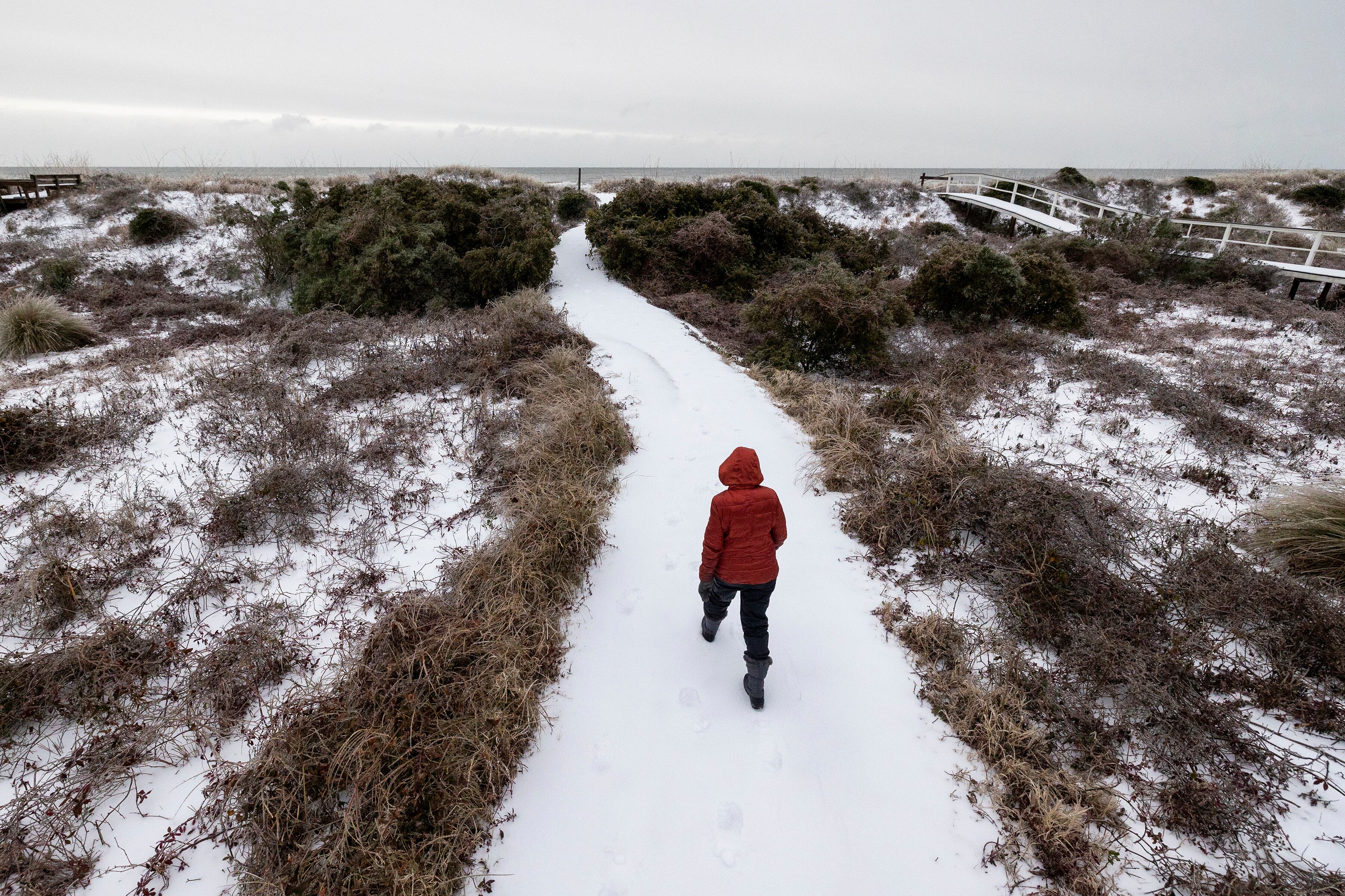 A beach walker heads to the ocean after a winter storm dropped ice and snow Wednesday, on the Isle of Palms, S.C.