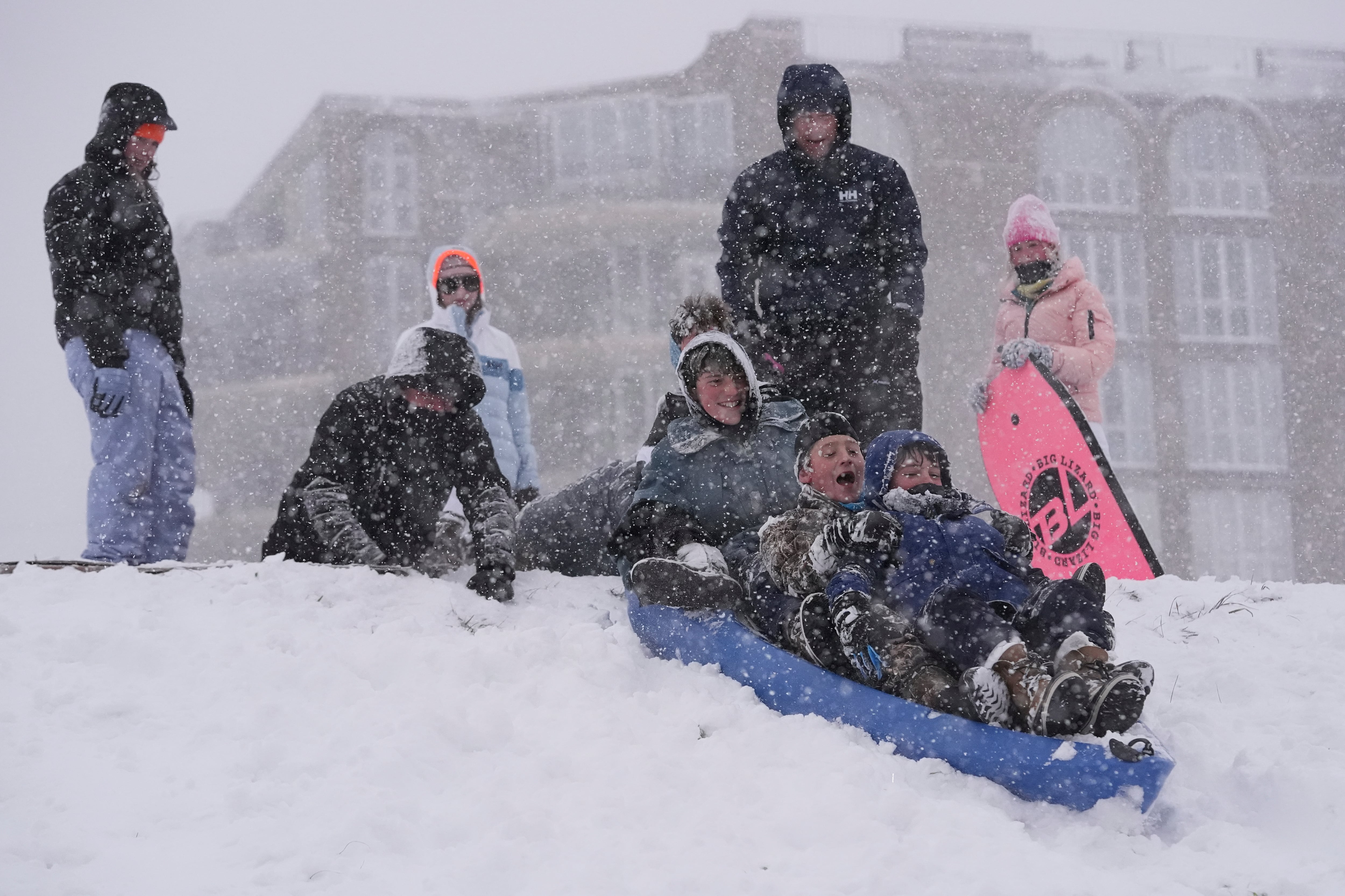 People sled on the backside of the Mississippi River levee as snow falls in New Orleans, Tuesday, Jan. 21, 2025.