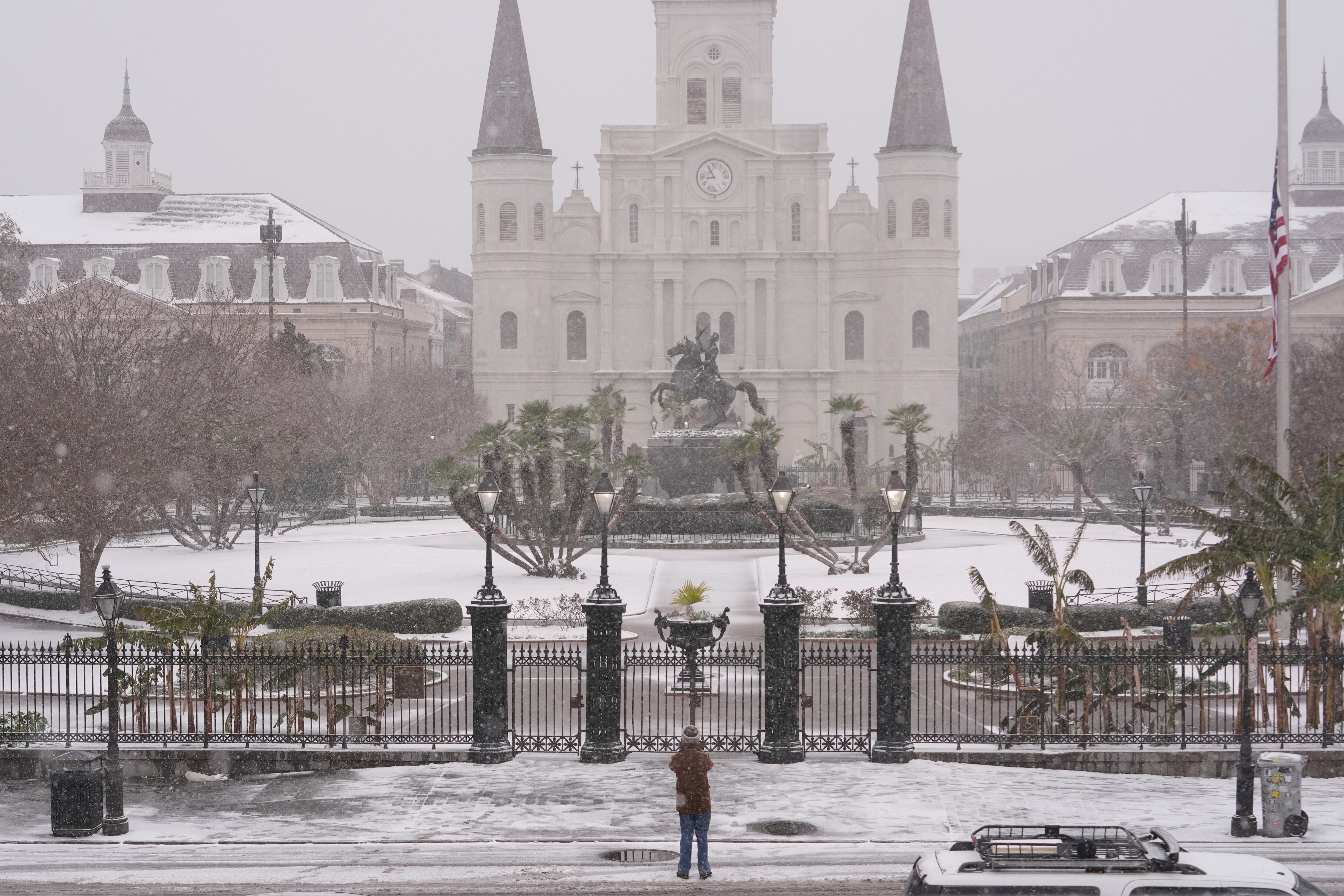 A person stops to take a picture at Jackson Square as snow falls in the French Quarter in New Orleans, Tuesday.