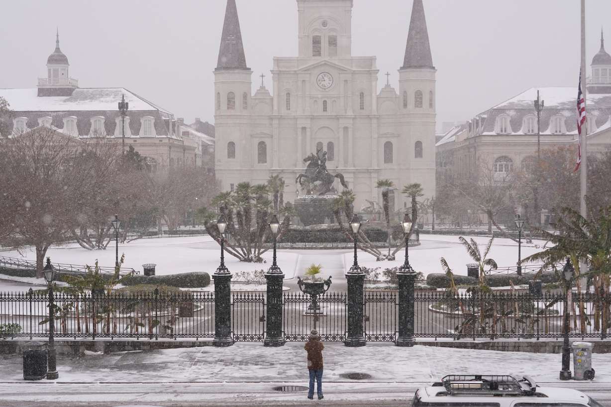 A person stops to take a picture at Jackson Square as snow falls in the French Quarter in New Orleans, Tuesday.