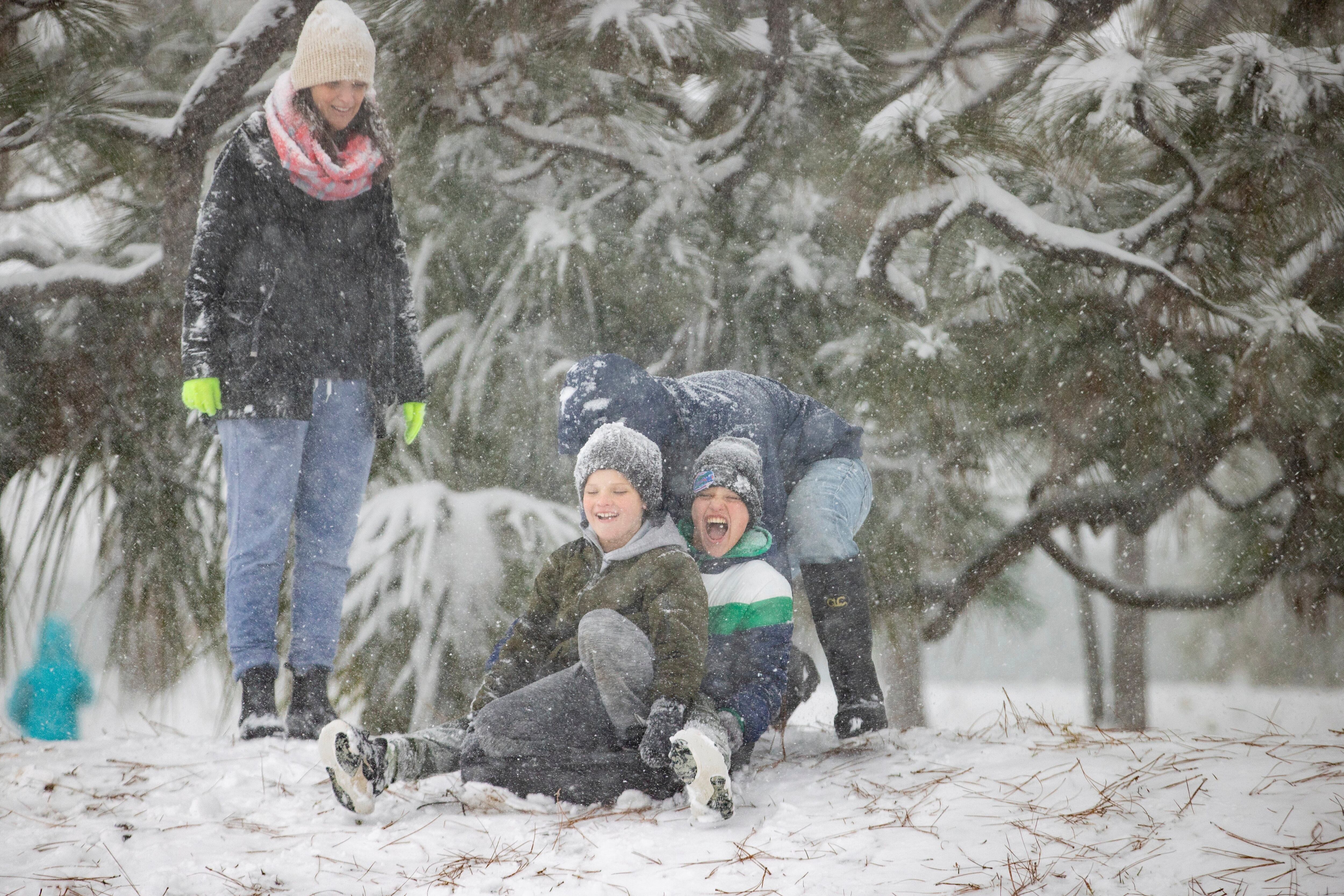 Families enjoy playing on snow at Bayview Park on Tuesday, in Pensacola, Fla.