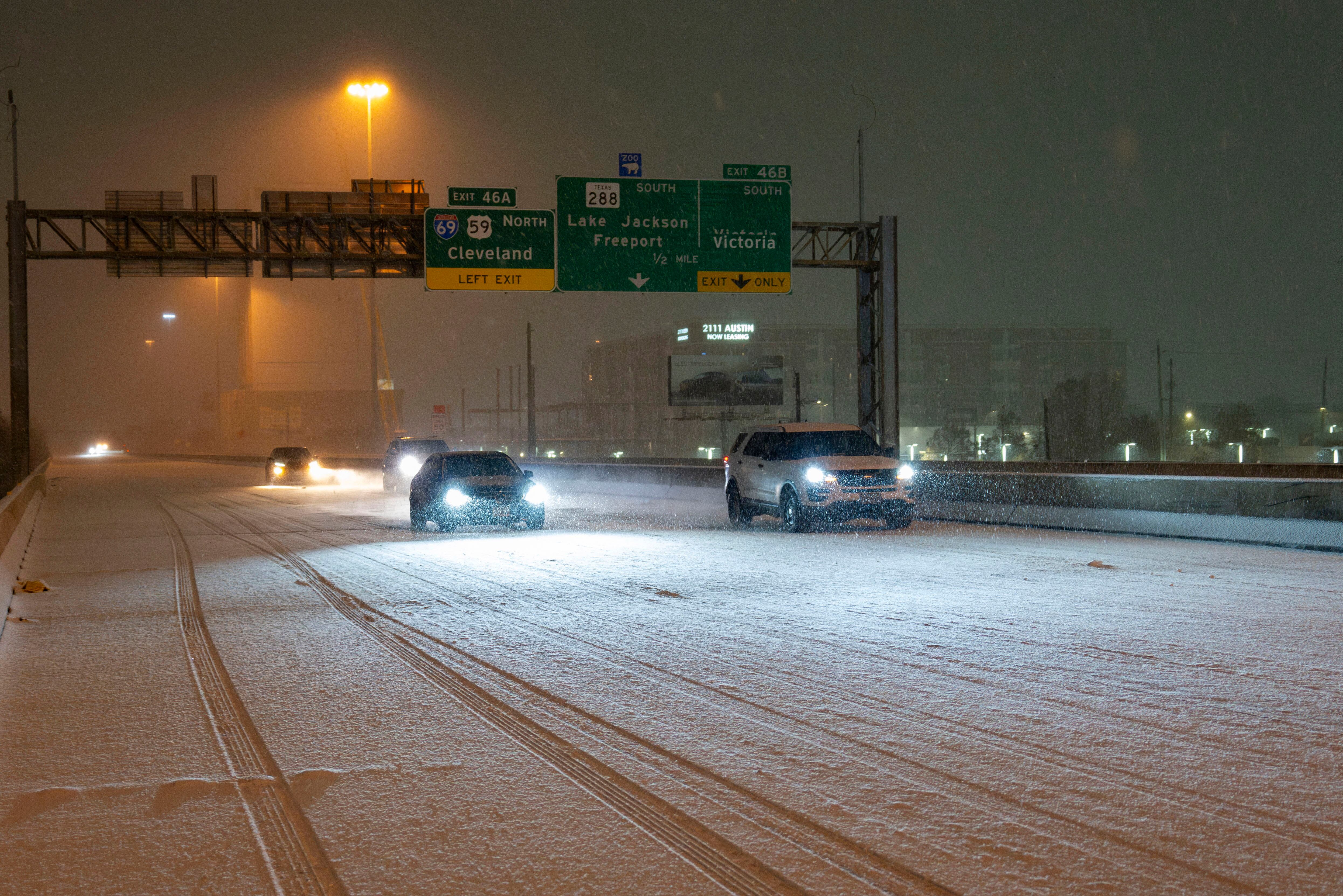 Snow covers the roadway as cars traverse I-45 Pierce Elevated northbound Tuesday, in Houston.