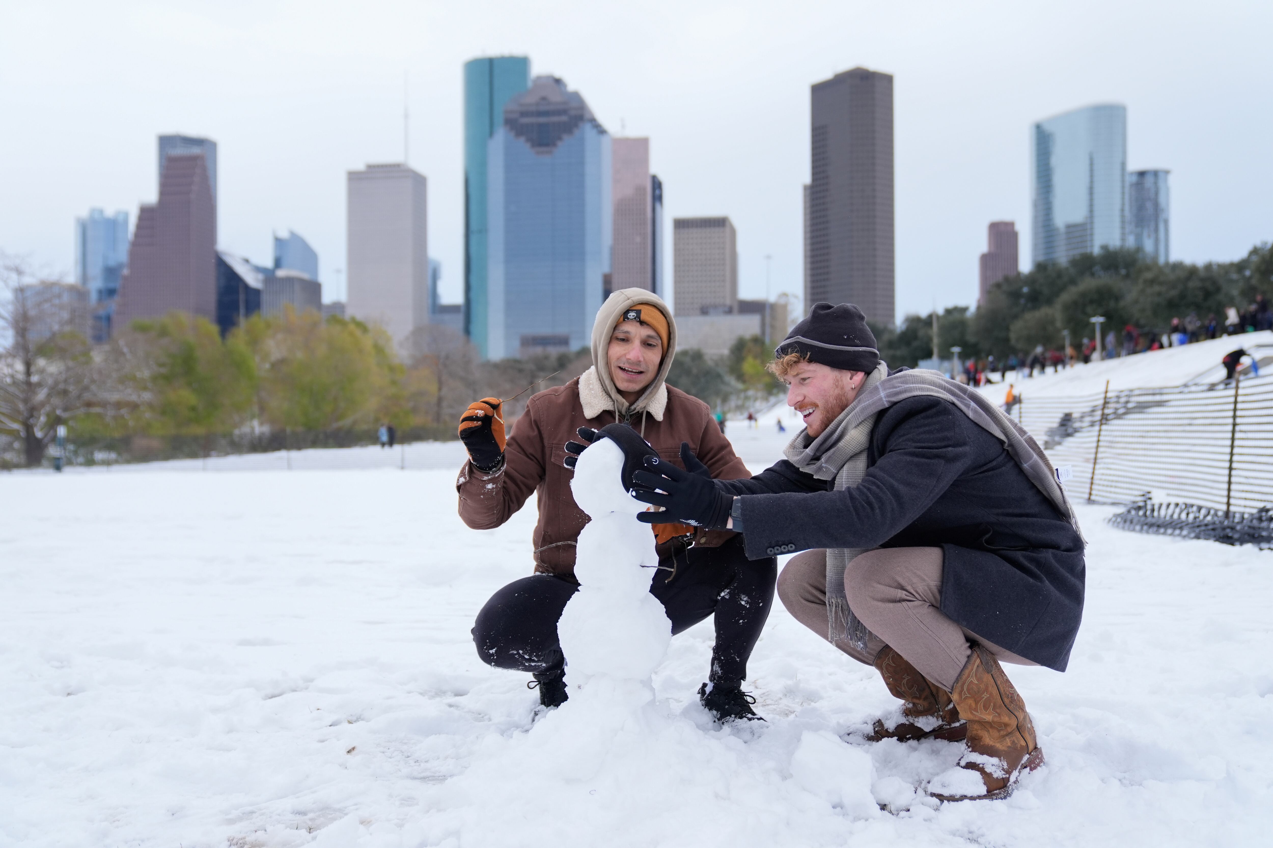 Adrian Santos, left, and Aaron Kenigsberg make a snowman along Buffalo Bayou in downtown Houston, Tuesday.