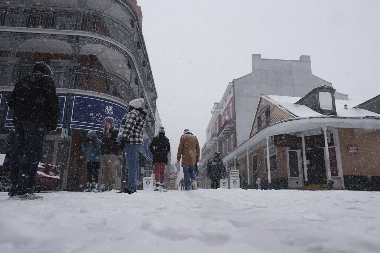 People walk in the French Quarter as snow falls in New Orleans on Tuesday.